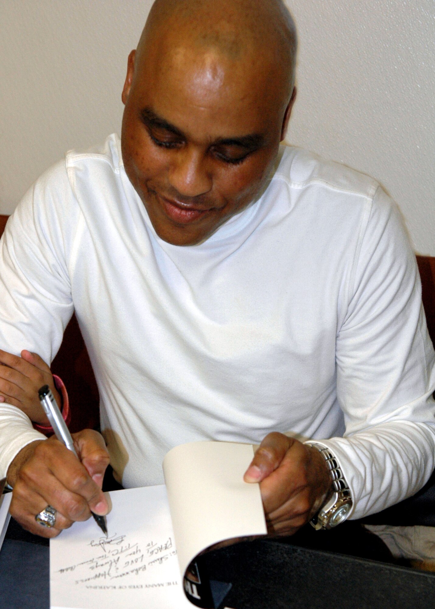 Tech. Sgt. Bruce Johnson signs a copy of his latest book, "The Many Faces of Katrina," during a book signing at the theater on Barksdale Air Force Base, La. Sergeant Johnson, a 755th Air Expeditionary Group information manager, has been a published author since 1994 and continues his writing while currently deployed to Bagram Air Base, Afghanistan. (U.S. Air Force photo/Tech. Sgt. Sherri Bohannon) 
