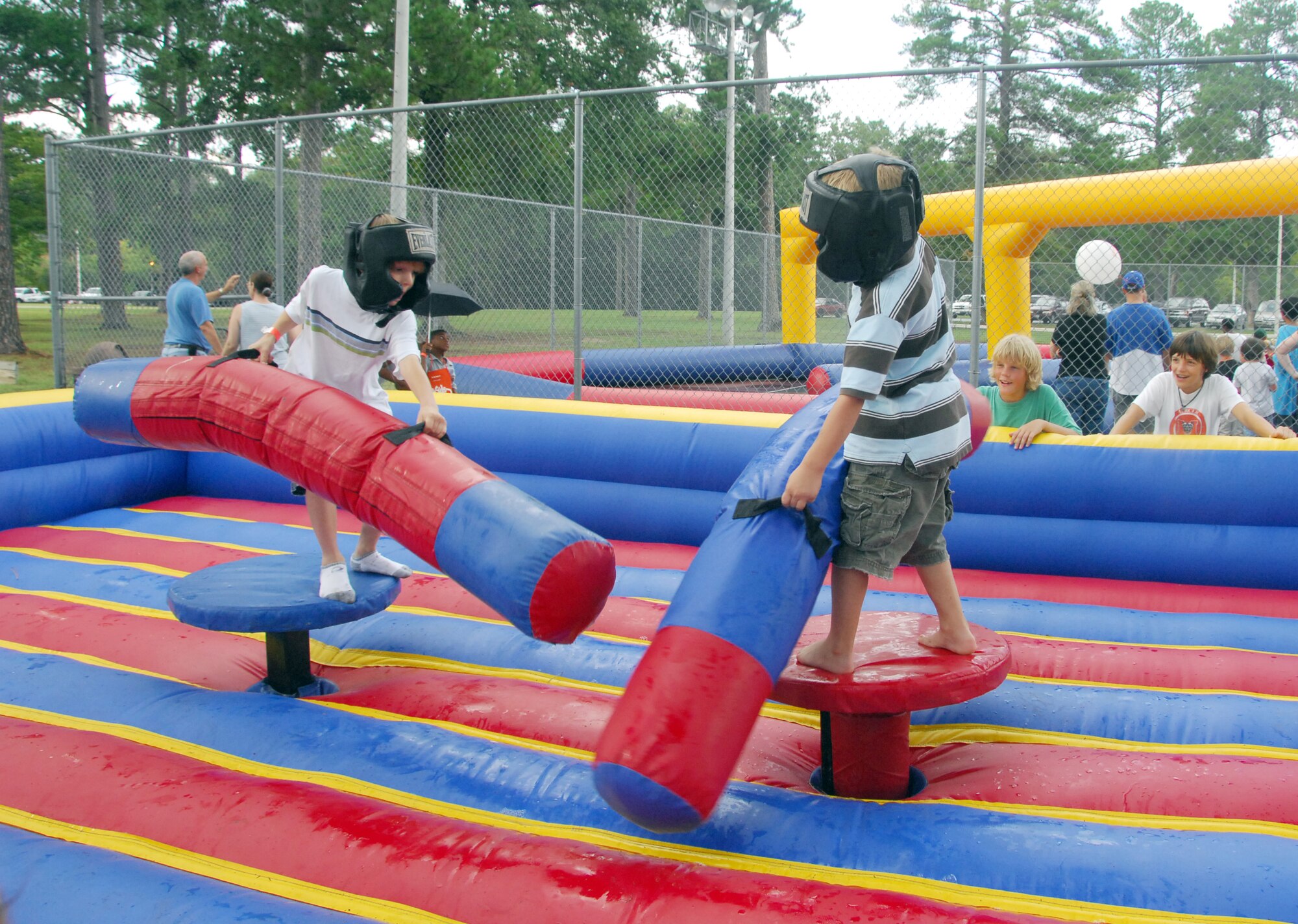 Two young attendees test each other’s balance at the 2007 Let’s Celebrate Summer Bash at Robins Park  while they are cheered on by onlookers.