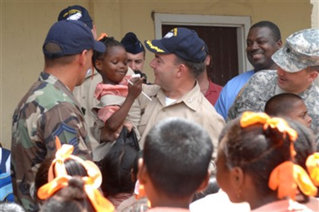 U.S. Navy Capt. Bob Kapcio, hospital ship USNS Comfort mission commander, gives a pencil to a student at the Grove Primary School in East Bank Demerara, Guyana, Sept. 26, 2007. Comfort is on a four-month humanitarian deployment to Latin America and the Caribbean.