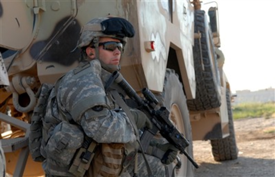 U.S. Army Capt. Keith Helms from Military Transition Team 0421, attached to 2nd Battalion, 27th Infantry Regiment, 3rd Brigade Combat Team, takes a knee behind an Iraqi vehicle after hearing small-arms fire during an Iraqi army cordon and search mission in Hawijah, Iraq, Sept. 22, 2007. 