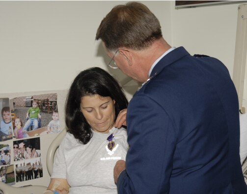 Air Force Reservist Senior Airman Diane Lopes, a security forces apprentice with the 920th Rescue Wing, Patrick Air Force Base, Fla. receives the Purple Heart Sept. 28 from the Chief of Air Force Reserve Command, Lt. Gen. John A. Bradley bedside at Walter Reed Army Medical Facility in Maryland.  Airman Lopes is in good condition and on the road to recovery despite surviving a mortar attack a week ago.  She and her fellow 920th RQW security forces comrades were in Iraq less than a month when Airman Lopes was struck by enemy shrapnel in the right arm and left leg while walking on base after a mortar attack. She was off duty at the time. She has endured several surgies for her injuries, but according to officials, her prognosis is good. (U.S. Army Photo/Winston S. Wilson)