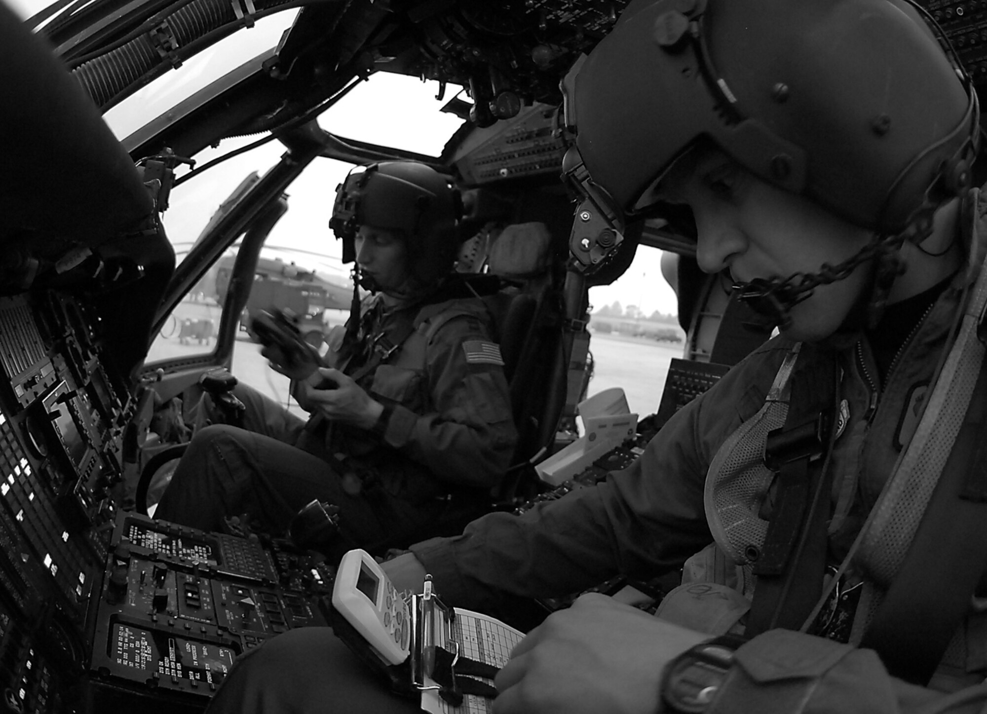Before a night training mission, 1st Lt. Mike Kingry, an HH-60G Pave Hawk co-pilot assigned to Moody's  41st Rescue Squadron, programs his navigational instruments, as Capt.  Jason Rodgers, the HH-60G's aircraft commander, prepares his night vision goggles. The 41st RQS Jolly Green Giants" routinely fly night missions to maintain proficiency in their primary mission combat search and rescue. (Photo by Tech. Sgt. Parker Gyokeres)