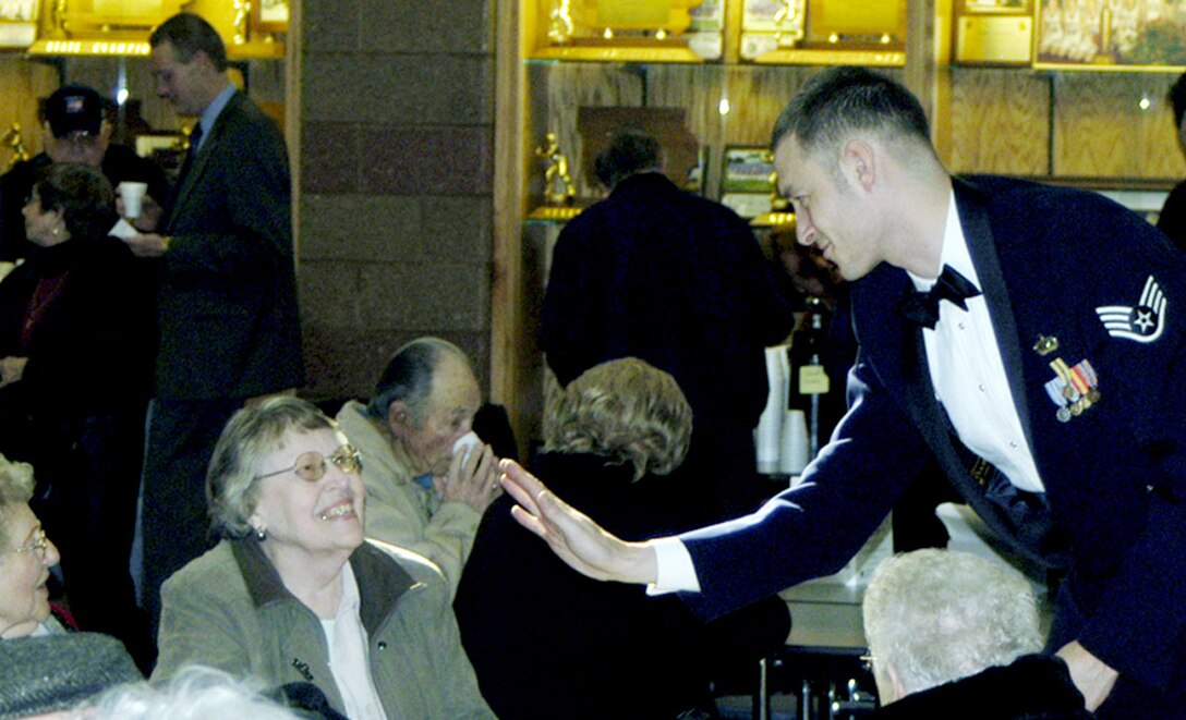 SSgt Matt Erickson, Noncommissioned Officer-in-Charge of the USAF Heartland of America Band's Brass in Blue, offers a 'high-five' to an audience member at a reception following a performance in Iowa.