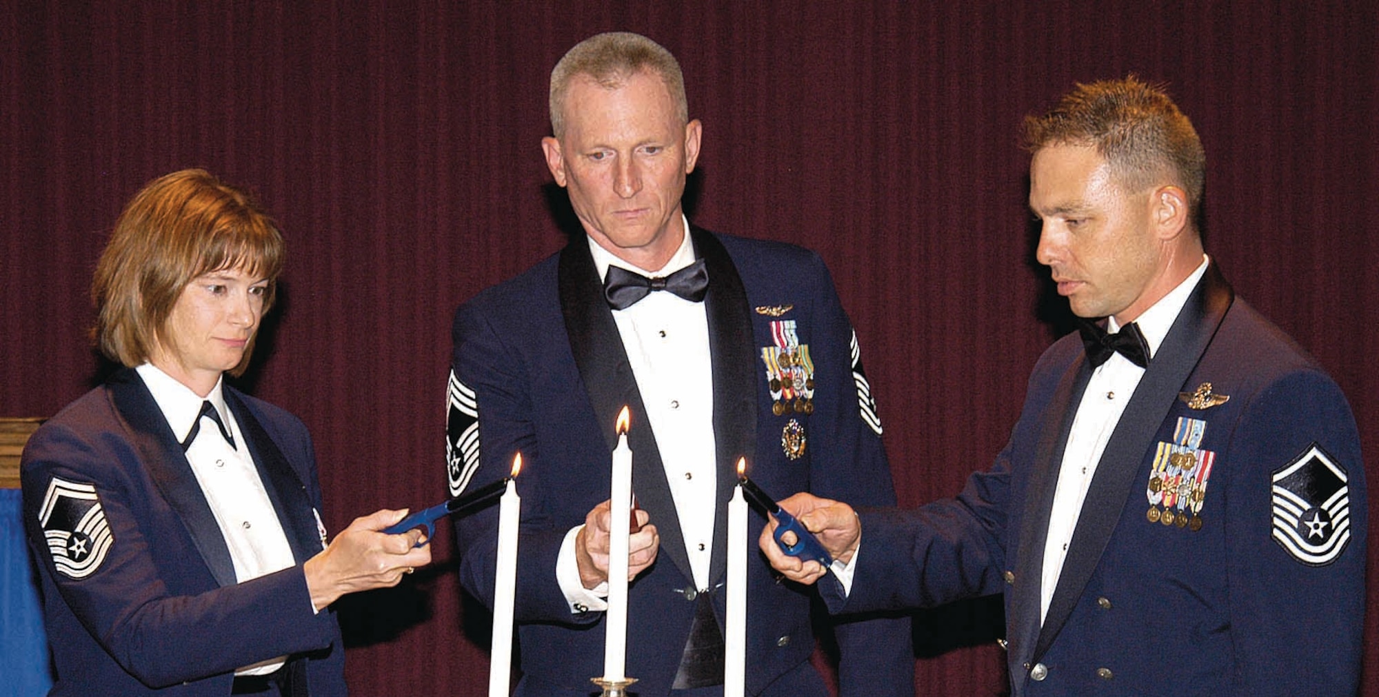 Senior Master Sgt. Bethann Fleming, Chief Master Sgt. Roddy Hartsook and Master Sgt. Don Lester, from left, light candles representing the three noncommissioned officer levels during the Sept. 21 Senior Noncommissioned Officers Induction Banquet at the Tinker Club. (Air Force photo by Margo Wright)
