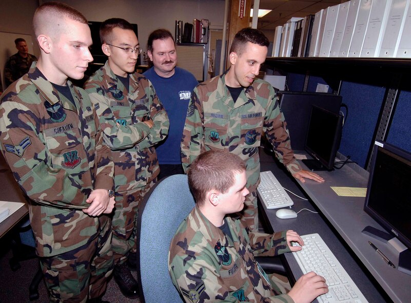 Airman 1st Class Joshua Cheathem, standing from left, Airman 1st Class Skyler Jones, James McDonald and Tech. Sgt. Brett Fincher look at a new change in the code. (Air Force photo)