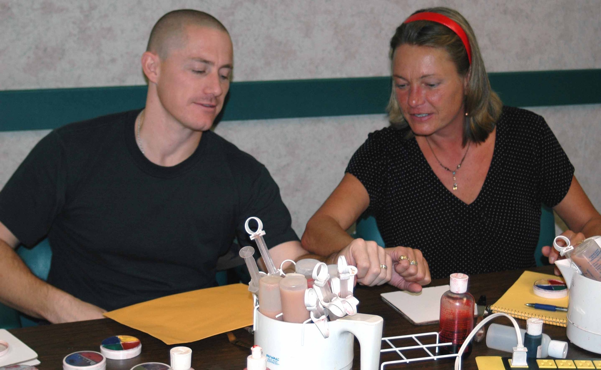 Kelly Van Etten and  552nd Air Control Wing Master Sgt. Ronnie Phillips, both part of the 552nd Wing Readiness Exercise office, compares injuries and bruises constructed during the moulage class. They are training to be moulage artists for wing exercises. (Air Force photo by Kandis West)