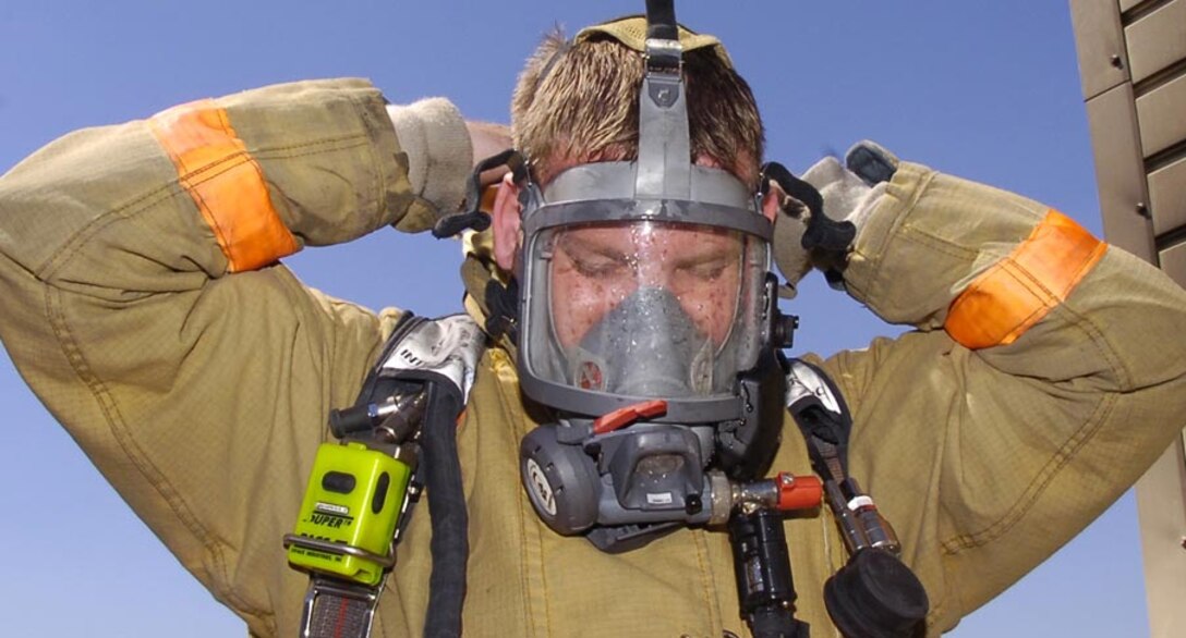 Christopher Boyd quickly dons a self contained breathing aparatus during fire training Sept. 12. (US Air Force/Bobby Jones)