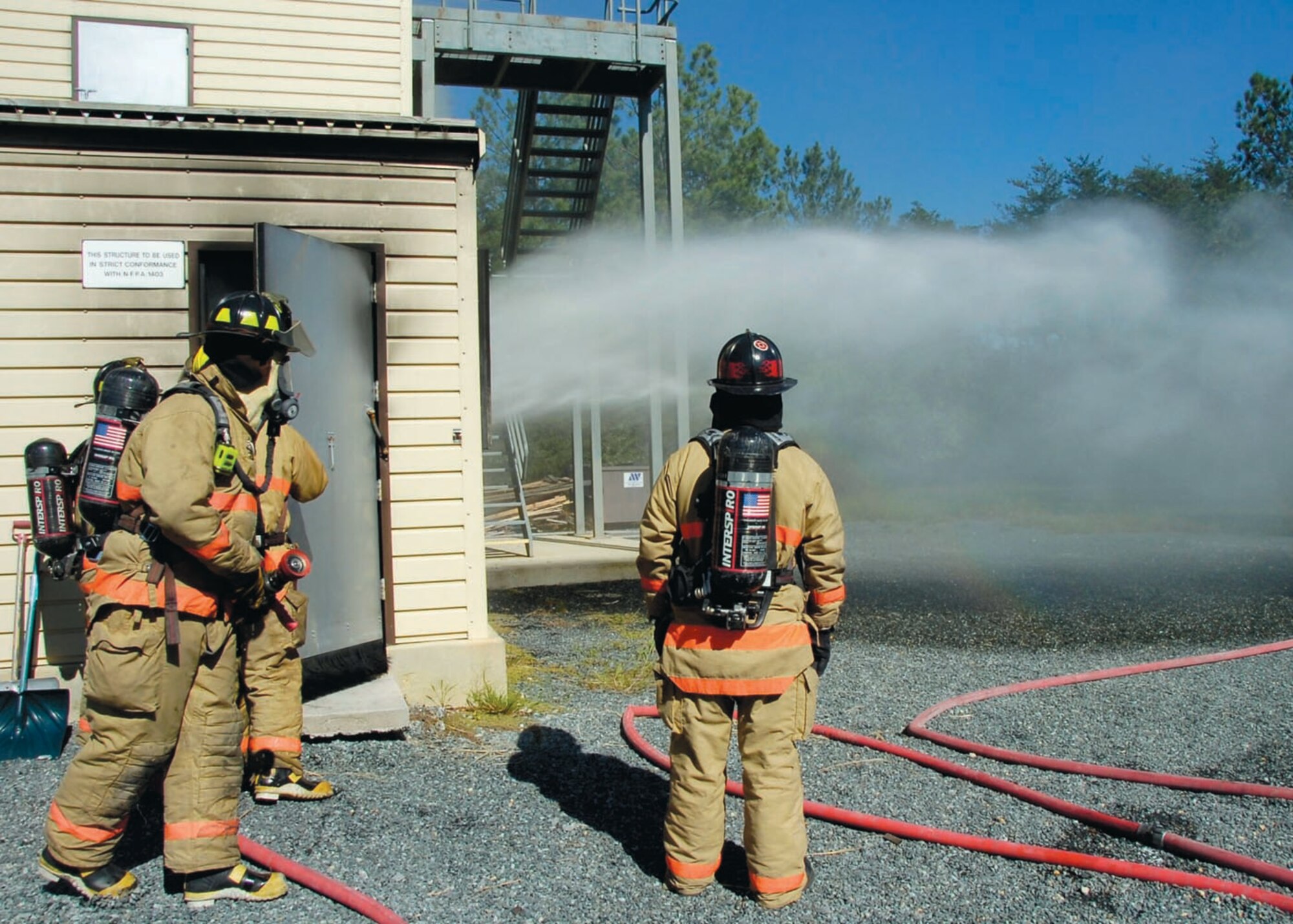A firefighter enters a simulated burning building during a training scenario Sept. 12.