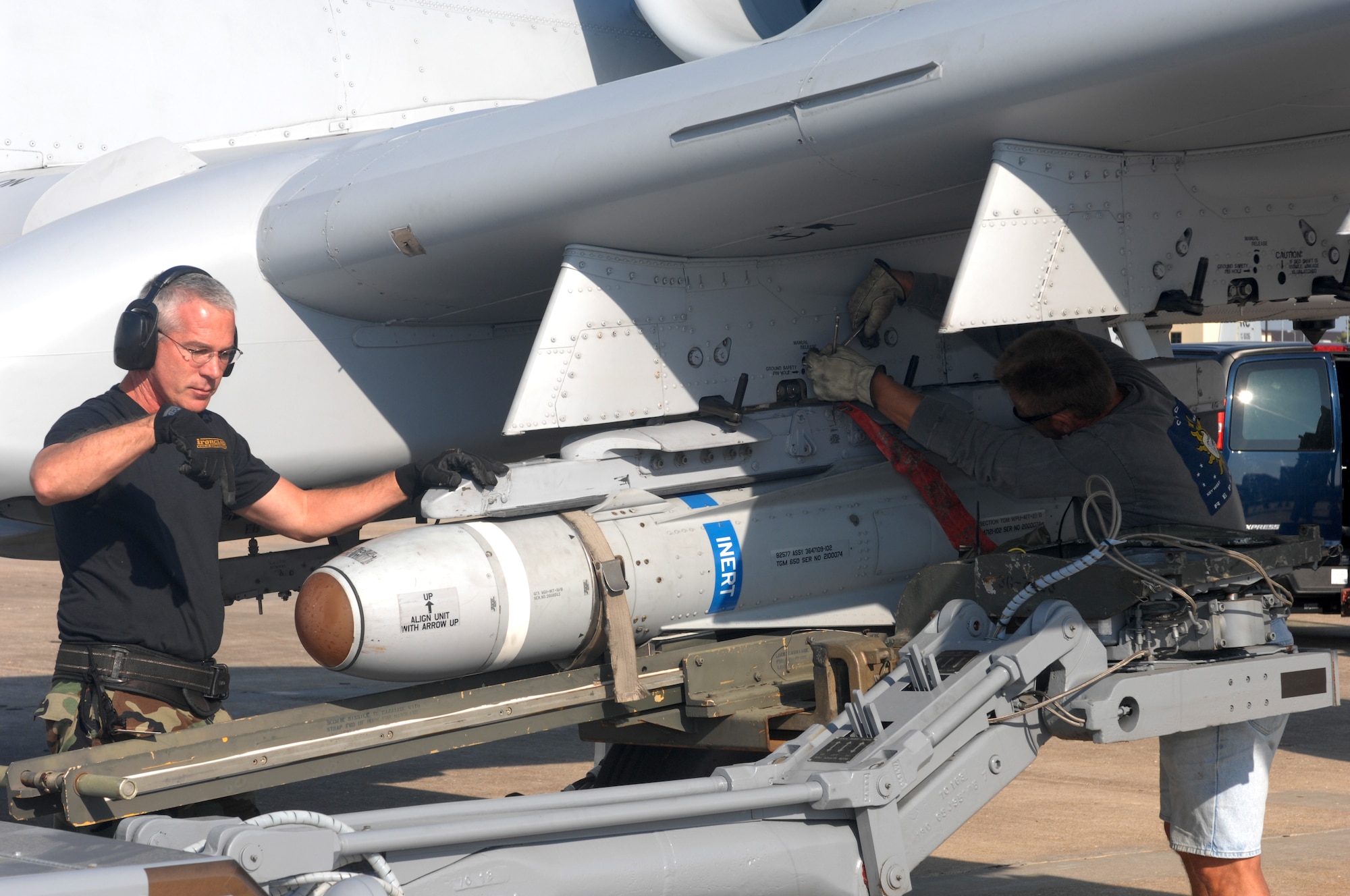 Master Sgt. Edward Coyle, 442nd Aircraft Maintenance Squadron, (left) gives commands through hand signals to the driver of a jammer while Jim Smitka, 442nd AMXS, locks an AGM-65 Maverick to a weapons pylon station Sept. 17. (U.S. Air Force photo/Tech. Sgt. Samuel A. Park)