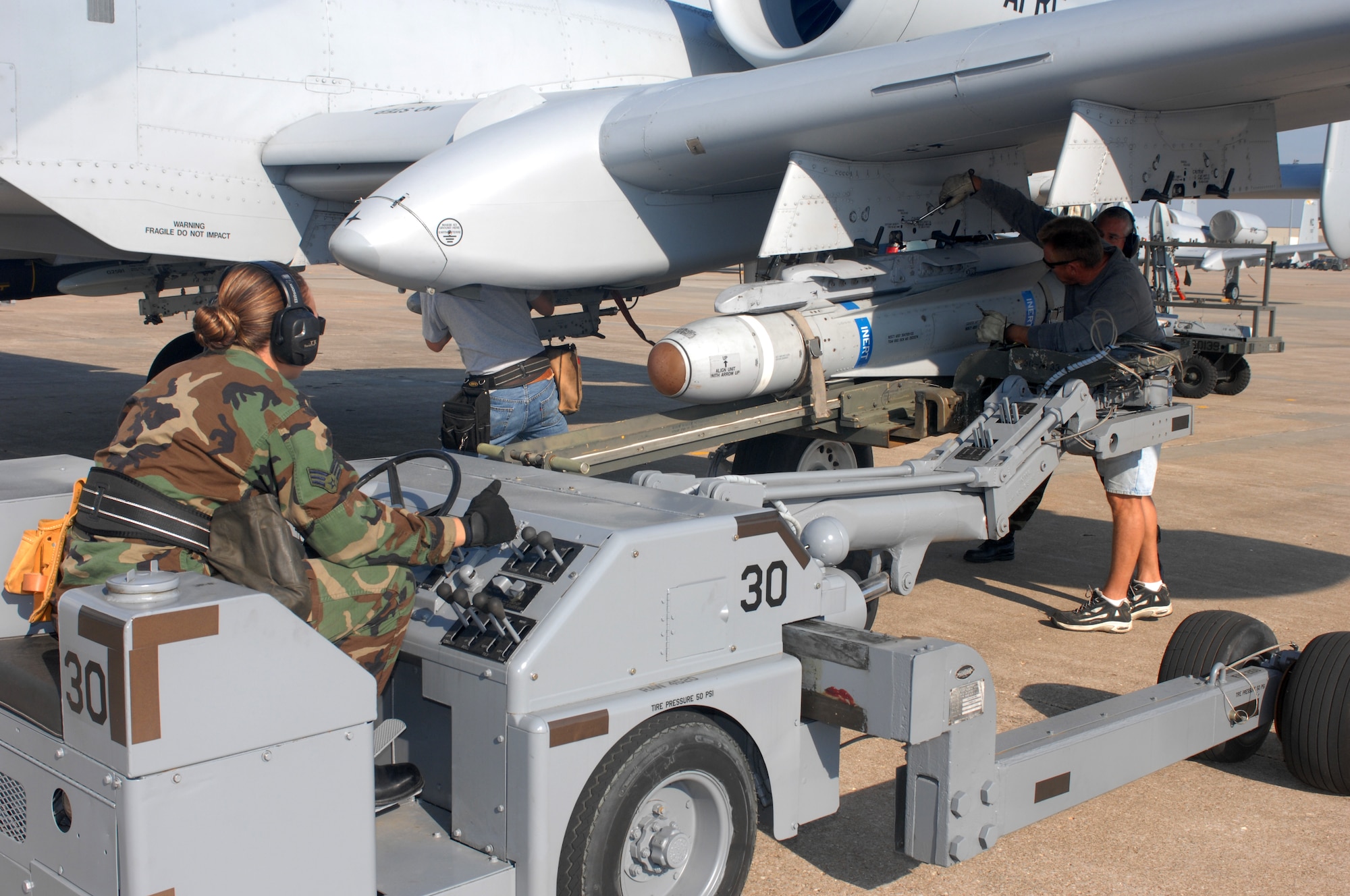 Senior Airman Jennifer Laspino, 442nd Aircraft Maintenance Squadron, adjusts the position of an AGM-65 Maverick on a jammer to line up with an A-10 weapons station. Edward Coyle and Jim Smitka, both from the 442d AMXS, prepare to lock the missile to the rack Sept. 17. Although the missiles are inert, pilots from the 442nd Fighter Wing fly training sorties with the missiles attached to practice targeting techniques. (U.S. Air Force photo/Tech. Sgt. Samuel A. Park) 