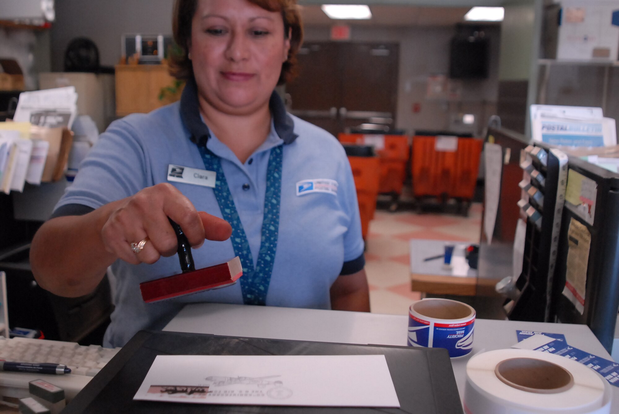 Clara Baez, Luke post office sales associate, stamps a letter with the Air Force 60th anniversary logo. The postmark will be available at the base post office until Oct. 18. (photo by Airman 1st Class C.J. Hatch)