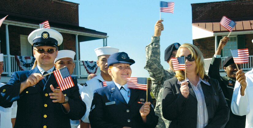 Airman 1st Class Anna M. Clarke, 316th Mission Support Squadron Military Personnel Flight outbound assignment technician, waves her miniature U.S. flag with 13 other joint-service immigrants after pledging her Oath of Allegiance during a natuarlization ceremony held at the Fort McHenry National Monument and Historic Shrine in Baltimore, Md., Sept. 23. (US Air Force/Bobby Jones)