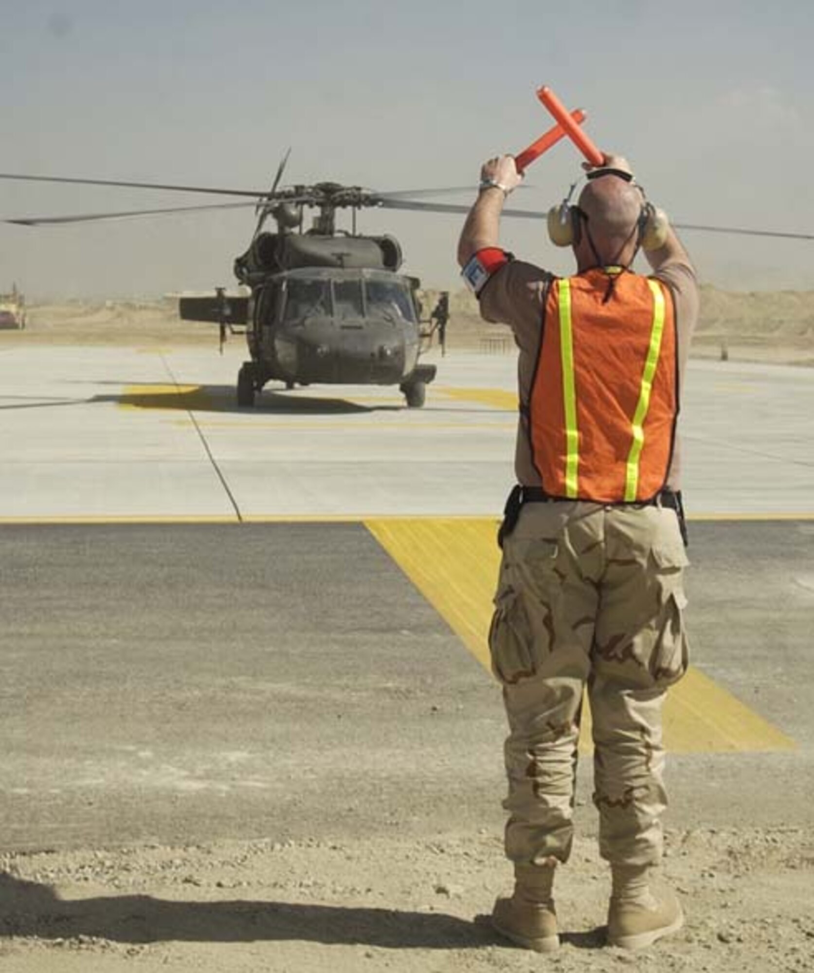 BAGRAM AIRFIELD, Afghanistan -- Master Sgt. Jamie Cabral of New Bedford, Mass, and a transient alert quality assurance evaluator for the 455th Air Expeditionary Wing here, marshals a helicopter on a brand-new ramp Sept. 27.  According to NATO and Air Force officials, the new ramp (one of two new ones officially opened on Sept. 27) will bring significant new capability for air support of Coalition forces.  (U.S. Air Force Photo by Capt. Michael Meridith)