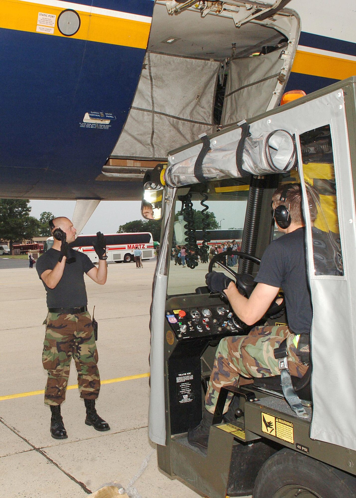 Senior Airman Matthew Hileman and Senior Airman Clancey Moulton, drive a mobile baggage conveyor up to an aircraft to offload baggage. (US Air Force/SrA Jeff Andrejcik)