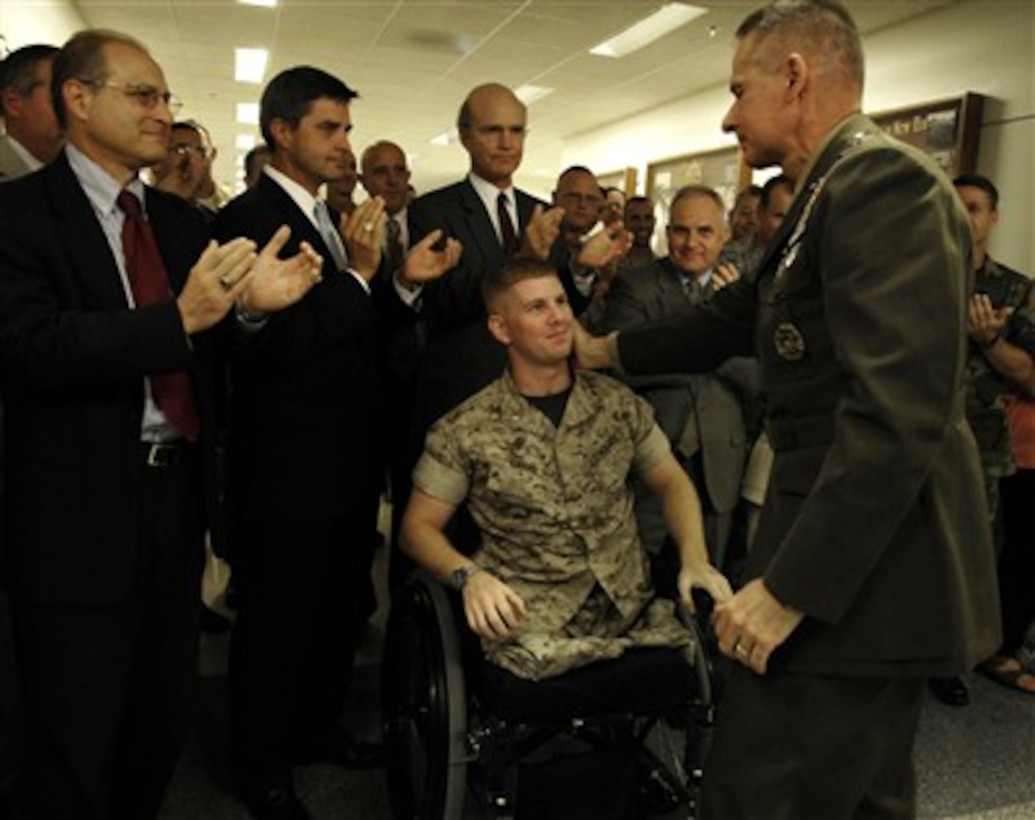 Chairman of the Joint Chiefs of Staff Gen. Peter Pace, U.S. Marine Corps, shares an emotional moment with a fellow U.S. Marine 1st Lt. Andrew Kinard in the Pentagon on Sept. 27, 2007, as DoD personnel applaud Pace on his last official day as chairman. 