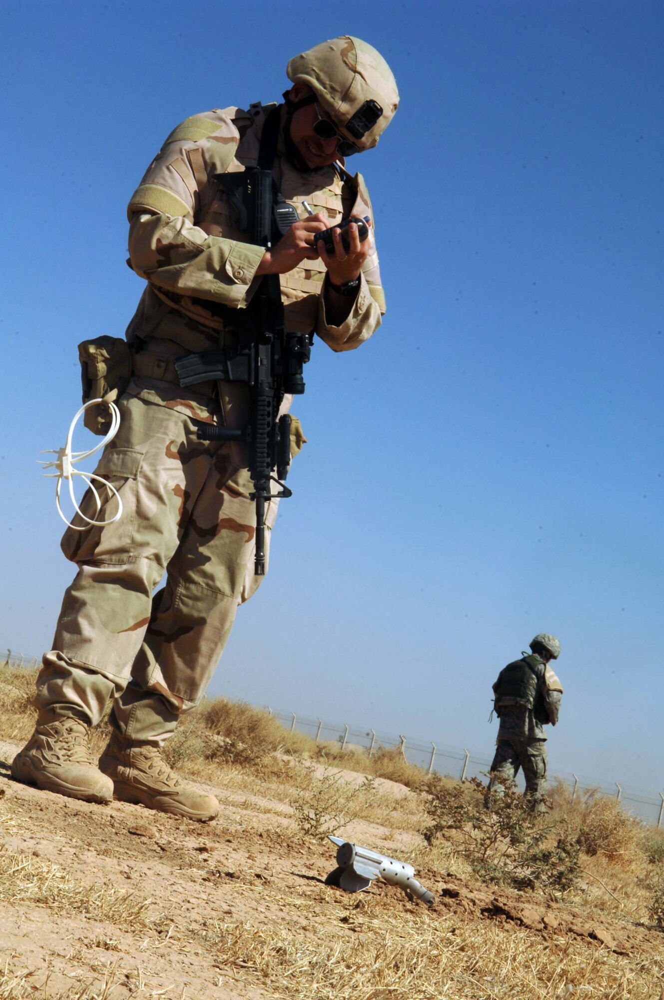 Staff Sgt. Thomas Sylvester, 332nd Expenditionary Security Forces Squadron, marks the point of impact with a GPS locator after an indirect fire attack during a recent training exercise, as Airman 1st Class Zachary Peel, also from 332 ESFS, posts a cordon to ensure the area is not breached. The members of the 332 ESFS  participate in routine exercises to ensure they are ready to respond during actual events. (U.S. Air Force photo by Joshua Garcia)