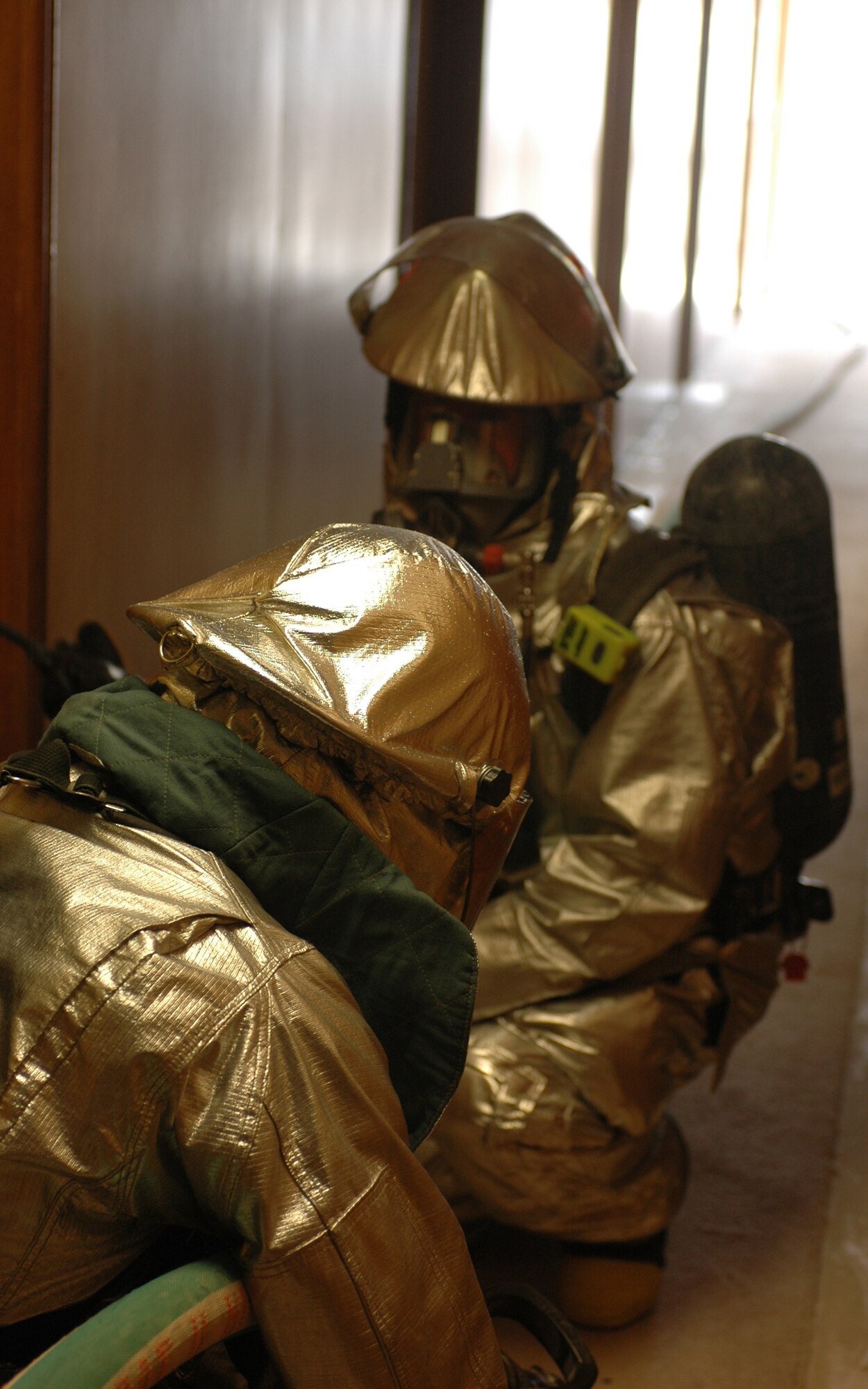 SOUTHWEST ASIA -- Airman 1st Class Trevor Nadile (front) and Tech. Sgt. Jason Barnard, 379th Fire Department kneel in front of a dorm room in building 22000 Wednesday during a morning exercise. Members of the 379th Fire Department take part in exercises daily to ensure they are prepared for real-world.  (U.S. Air Force photo/ Staff Sgt. Jason Barebo)