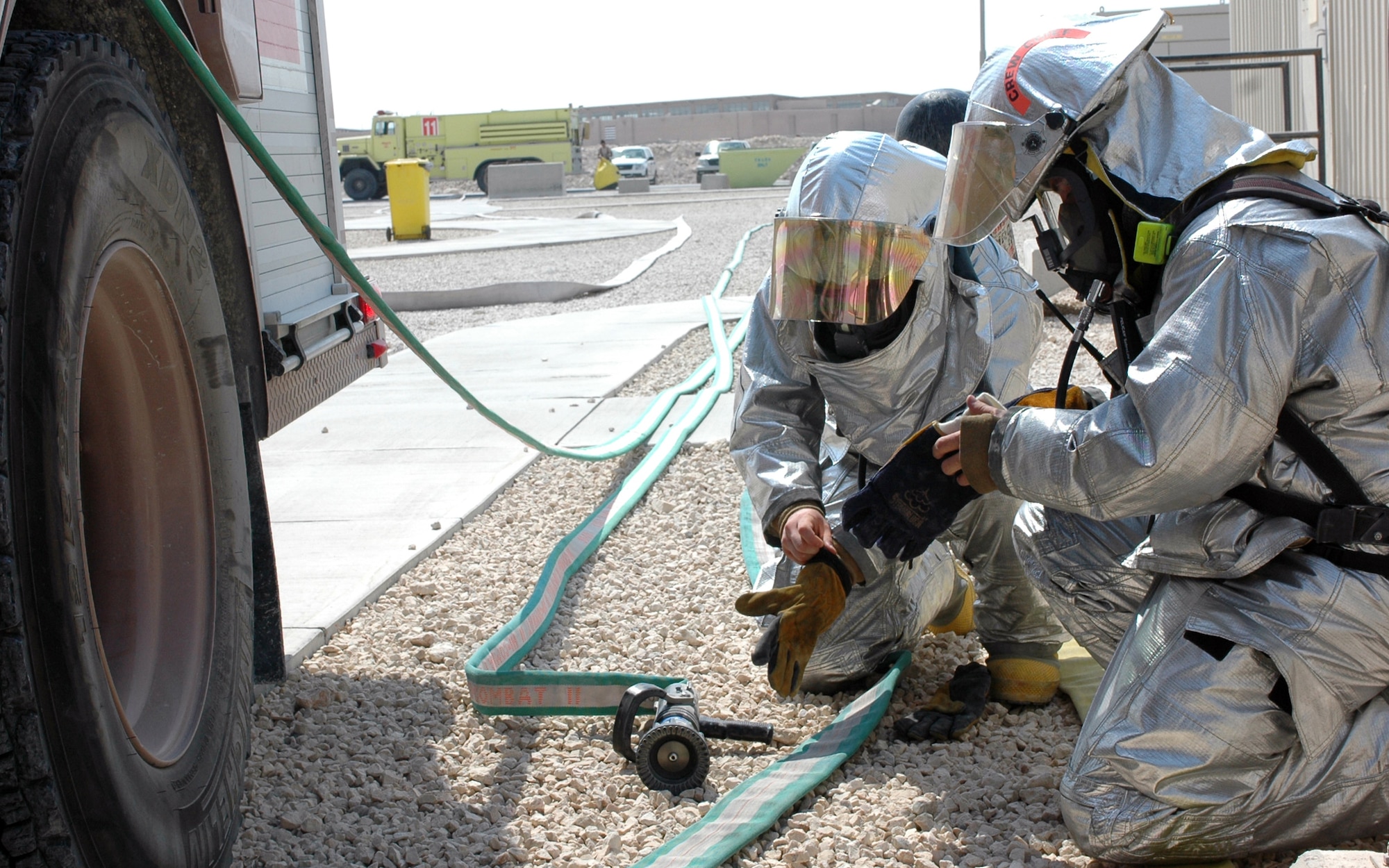 SOUTHWEST ASIA -- Tech. Sgt. Jason Barnard (front) and Airman 1st Class Trevor Nadile, 379th Fire Department, don their oxygen masks and fire retardant gear during an exercise Wednesday. The “silver suits” add 40 - 50 degrees of heat to the already 100 plus degree temperatures.  (U.S. Air Force photo/ Staff Sgt. Jason Barebo)