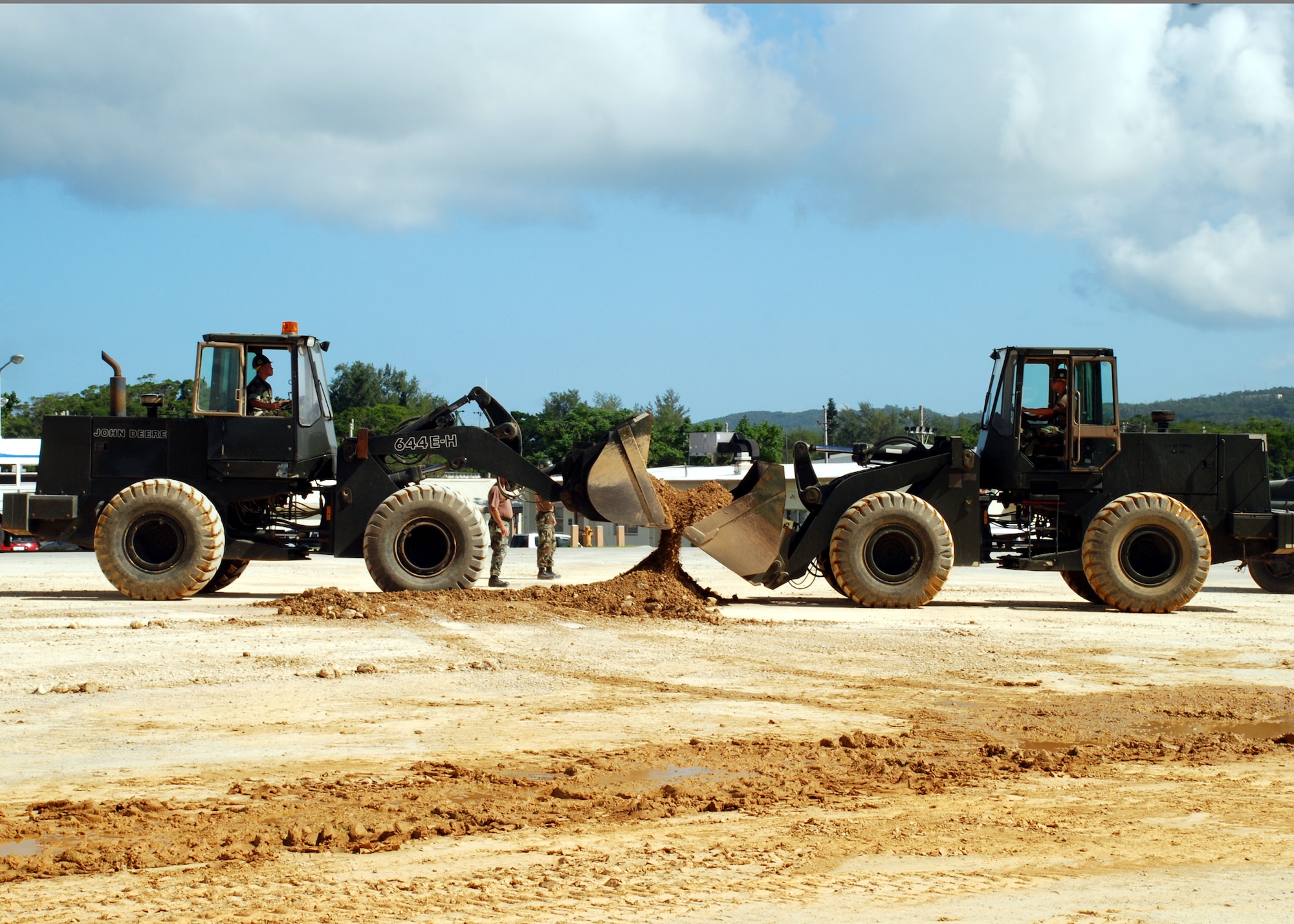 Equipment Operator 2nd Class (AW) Gerald Flint and Equipment Operator Constructionman Jonathan Montoro cooperatively use front end loaders to scoop up the remaining pile of soil to fill a simulated crater September 25, 2007 in a simulated runway on Kadena Air Base as part of a joint-training exercise with the U.S. Air Force. Naval Mobile Construction Battalion (NMCB) 7 personnel partnered with Kadena airmen from RED HORSE (Rapid Engineer Deployable Hevy Operation Ready Squadron Engineers). NMCB 7 is currently deployed to the Far East to provide construction support to shore installations in support of the global war on terrorism. (U.S. Navy photo/Mass Communication Specialist 2nd Class Michael B. Lavender)