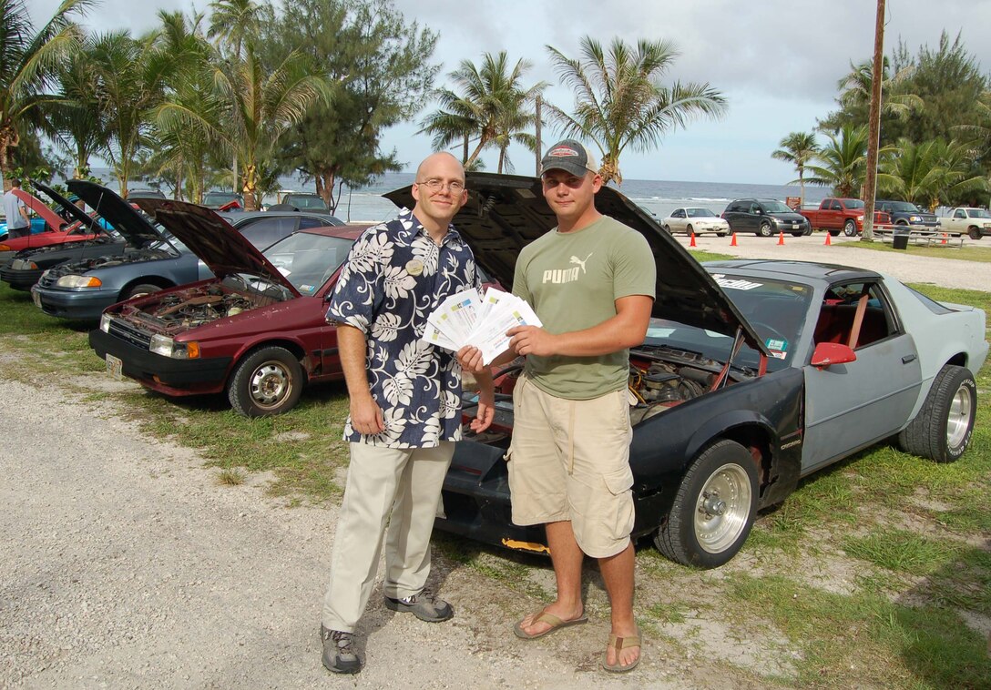Second Lieutenant Marc Morin, 36th Services Squadron, presents Boonie Car Contest winner, Airman 1st Class John Lamb, 36th Civil Engineer Squadron, with $500 Services bucks towards fixing his vehicle at the Auto Hobby Shop.  Airman Lamb’s 1986 Chevy Camaro took the prize as his exhaust system spouted puffs of black smoke when started; the quarter panel was on the verge of coming off; the lights were falling out of place; the seats were crooked; and the outside was painted in four different shades. (U.S. Air Force photo/Senior Airman Angelique Smythe)