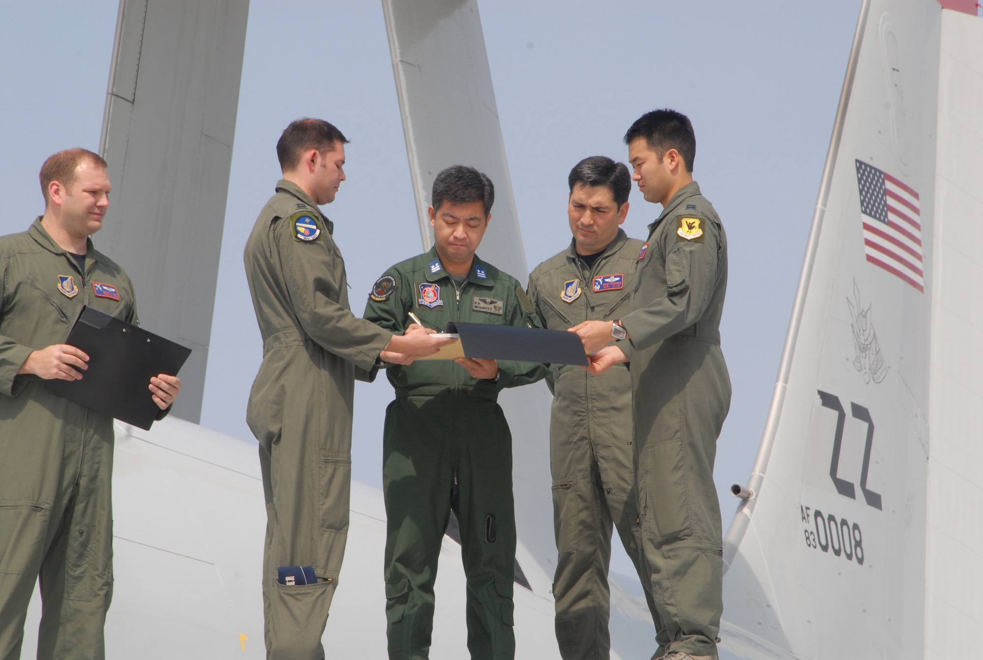 Japan Air Self-Defense Force Lt. Col. Miyamoto Hironori (center), 602nd Airborne Air Control Squadron commander, signs a sister squadron agreement March 26 as Lt. Col. Rene Romero (second from right), 961st AACS commander, looks on. The agreement formalized the joint working relationship enjoyed by the two squadrons. This was the first sister squadron agreement between a Kadena Air Base unit and JASDF. (U.S. Air Force photo/Senior Airman Nestor Cruz)