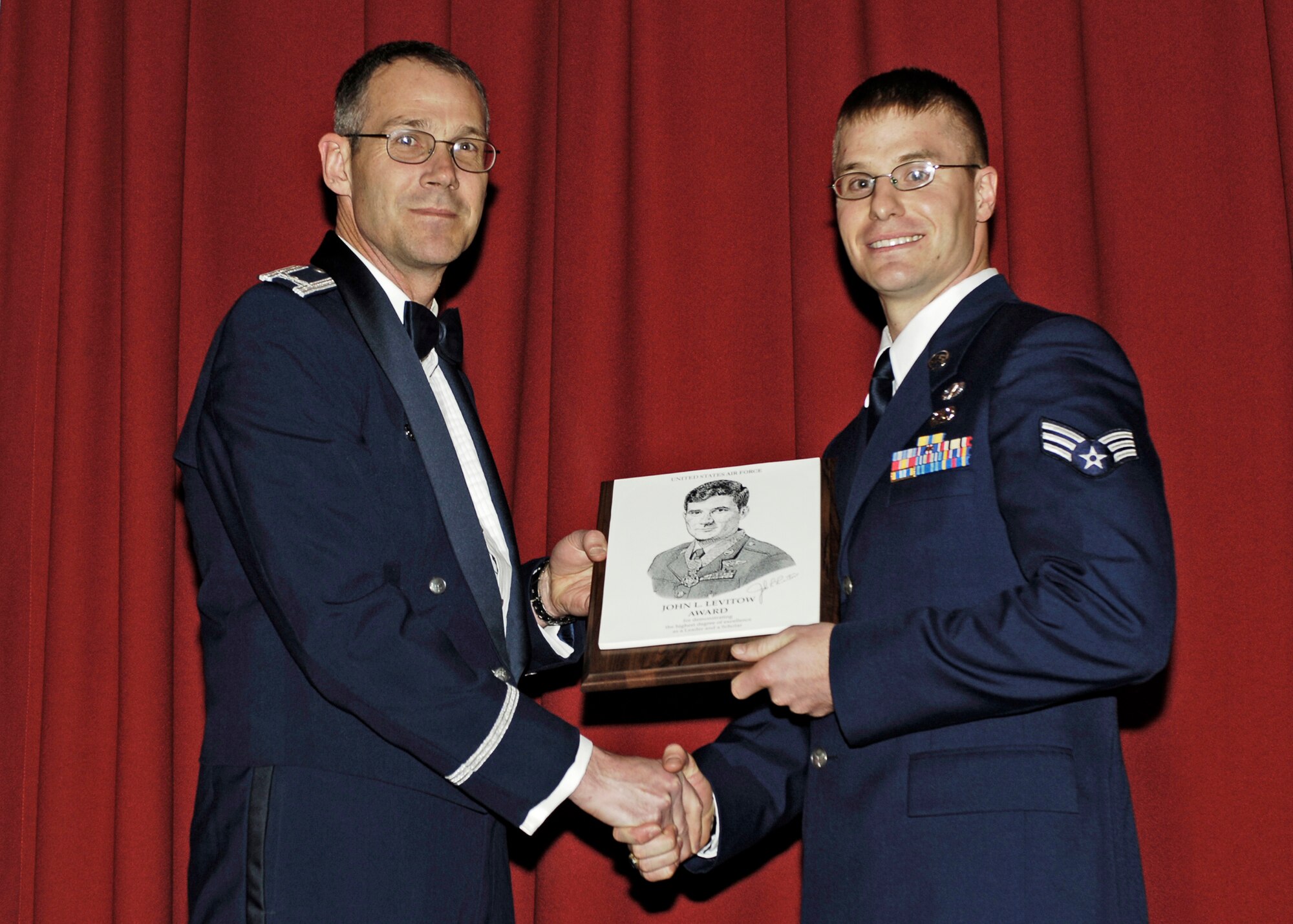 FAIRCHILD AIR FORCE BASE, Wash. – Col. Mark Melville, 92nd Operations Group commander, presents Senior Airman Brian Daubert with the John L. Levitow award for demonstrating the highest degree of excellence as a leader and scholar. The award was given during the Airman Leadership School graduation at Club Fairchild March 27.  (U.S. Air Force photo / Airman First Class Melissa Barnett )