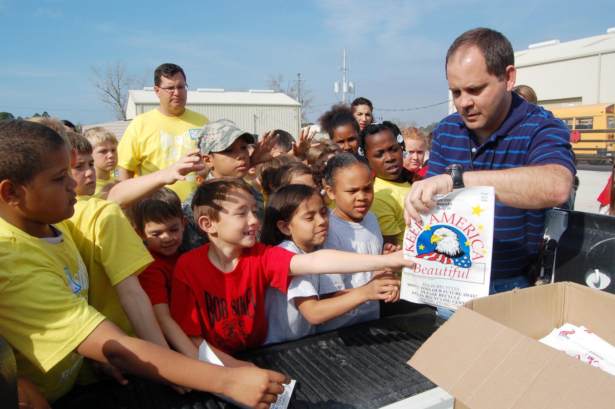 EGLIN AIR FORCE BASE, Fla. -- Excited students from Bob Sikes Elementary School in Crestview, Fla, reach for goody bags as Mark Taylor, Eglin Recycling Center manager, hands them out after a tour of the Eglin Recycling Center Thursday. Over the course of three days, more than 160 students, parents and teachers from the school toured the Eglin Recycling Center to learn more about how Eglin recycles various materials. (U.S. Air Force photo/ Jerron Barnett)
