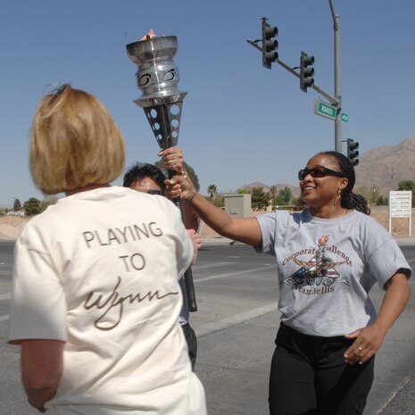 Ms. Tracie Atkins, Family Childcare Coordinator, assigned to the 99th Services Squadron, hands the torch over to Team Wynn during the corporate challenge torch relay event March 26, 2008, Las Vegas, Nev.(U.S. Air Force Photo by/Senior Airman Larry E. Reid Jr.)