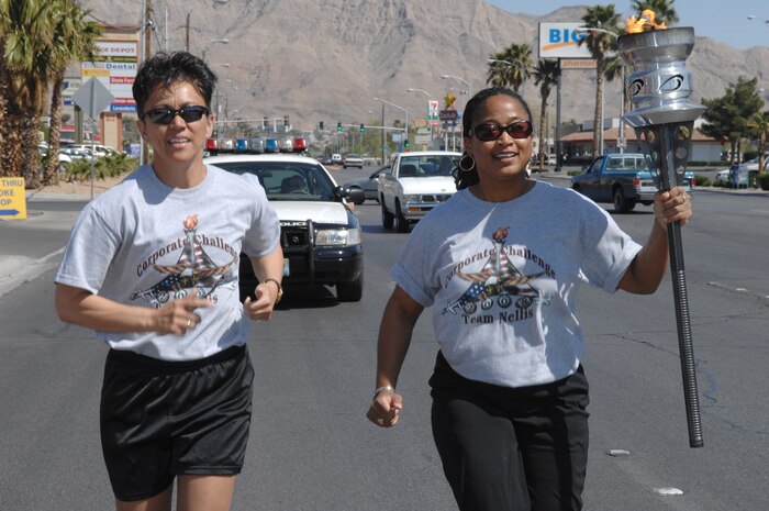 LAS VEGAS -- Carol Padilla (left), Youth Center director, and Tracie Atkins, family childcare coordinator, both assigned to the 99th Services Squadron, carry a torch for Team Nellis during the Las Vegas Corporate Challenge torch relay March 26. (U.S. Air Force Photo/Senior Airman Larry E. Reid Jr.)