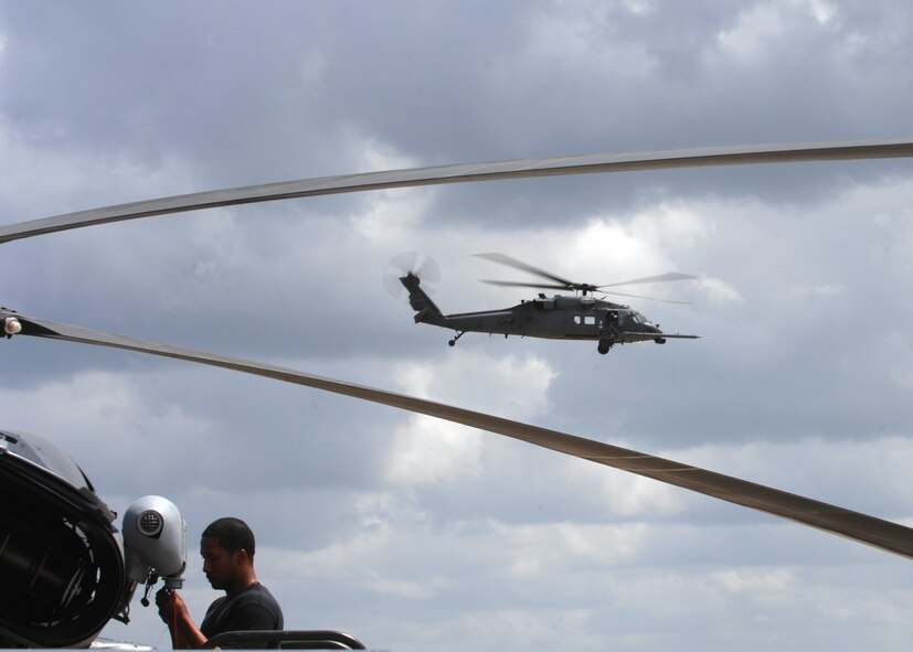 MOODY AIR FORCE BASE, Ga. -- Staff Sgt. Ray Campbell, 723rd Aircraft Maintenance Squadron HH-60G Pave Hawk electrical and environmental craftsman, installs a hoist cable squib on a HH-60G Pave Hawk while another flies by in the background here April 1. The primary mission of the Pave Hawk is to conduct combat search and rescue operations. (U.S. Air Force photo by Airman 1st Class Brittany Barker)  