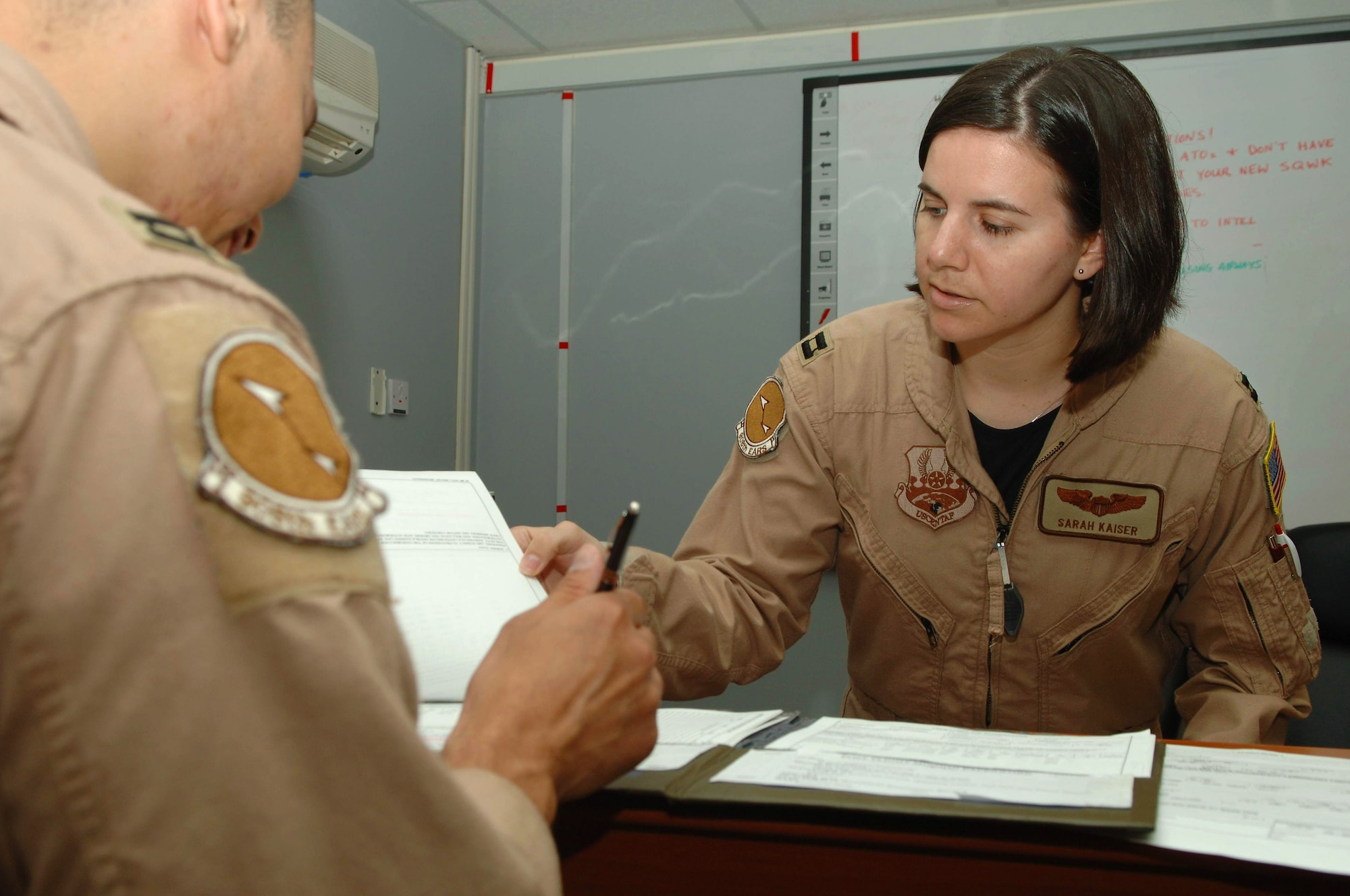 Capt. Sarah Kaiser gives mission paperwork to a KC-10 Extender aircrew member prior to a mission brief April 1 at a base in Southwest Asia. Providing 6.5 million pounds of jet fuel weekly, the KC-10 and the Airmen of the 380th Air Expeditionary Wing who support it give global reach to U.S. and coalition aircraft supporting operations Enduring Freedom and Iraqi Freedom. Captain Kaiser is the 908th Expeditionary Air Refueling Squadron assistant director of operations. (U.S. Air Force photo/Senior Airman Levi Riendeau)
