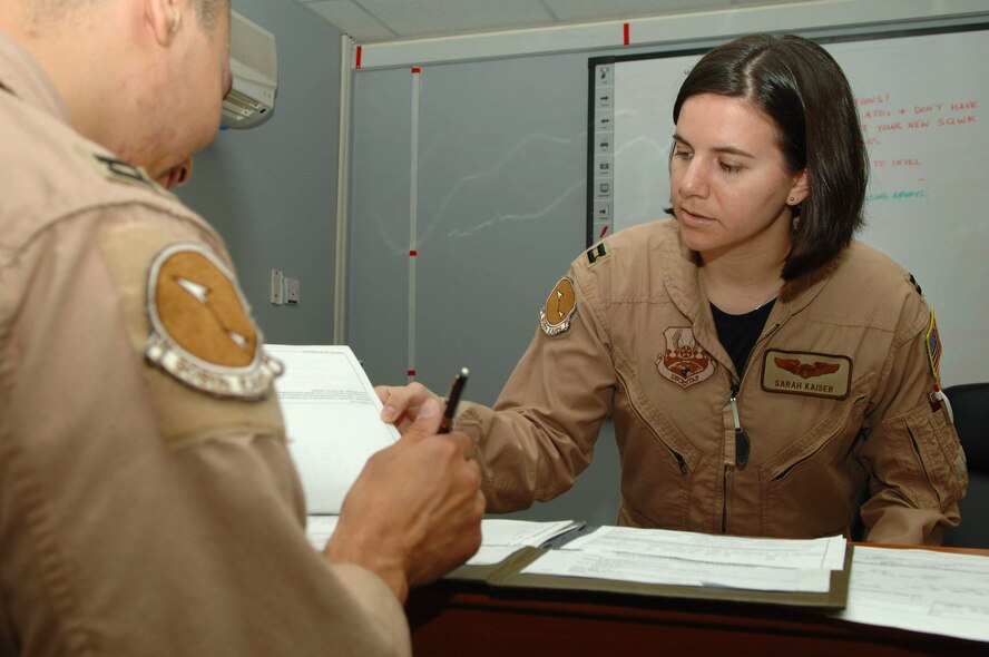 Capt. Sarah Kaiser gives mission paperwork to a KC-10 Extender aircrew member prior to a mission brief April 1 at a base in Southwest Asia. Providing 6.5 million pounds of jet fuel weekly, the KC-10 and the Airmen of the 380th Air Expeditionary Wing who support it give global reach to U.S. and coalition aircraft supporting operations Enduring Freedom and Iraqi Freedom. Captain Kaiser is the 908th Expeditionary Air Refueling Squadron assistant director of operations. (U.S. Air Force photo/Senior Airman Levi Riendeau)