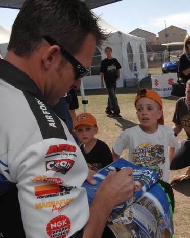 Damon Bradshaw, driver of the U.S. Air Force Afterburner monster truck, autograph a young fans event program during a meet and greet session at the Monster Jam World Finals in Las Vegas, Nev., March 29, 2008. (U.S. Air Force Photo by/Senior Airman Larry E. Reid Jr.)(Released)