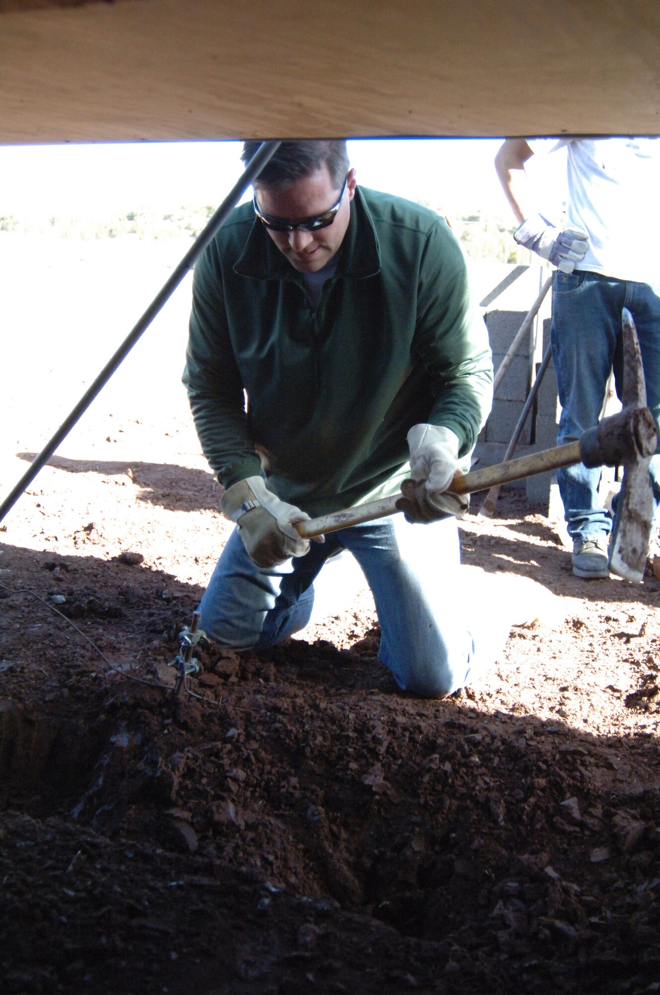 Maj. John Christ  puts his civil engineering knowledge to work as he uses a pick-axe to dislodge frozen ground at a volunteer worksite March 26 in Navajo, N.M. The frozen soil would be replaced by cinderblocks and concrete, to become the foundation of a home for a Navajo family. Major Christ is an instructor at the Air Force Academy's Department of Civil Engineering. He and a group of 20 cadets, faculty and family members volunteered to work at the reservation during the Academy's spring break. (U.S. Air Force photo/John Van Winkle)