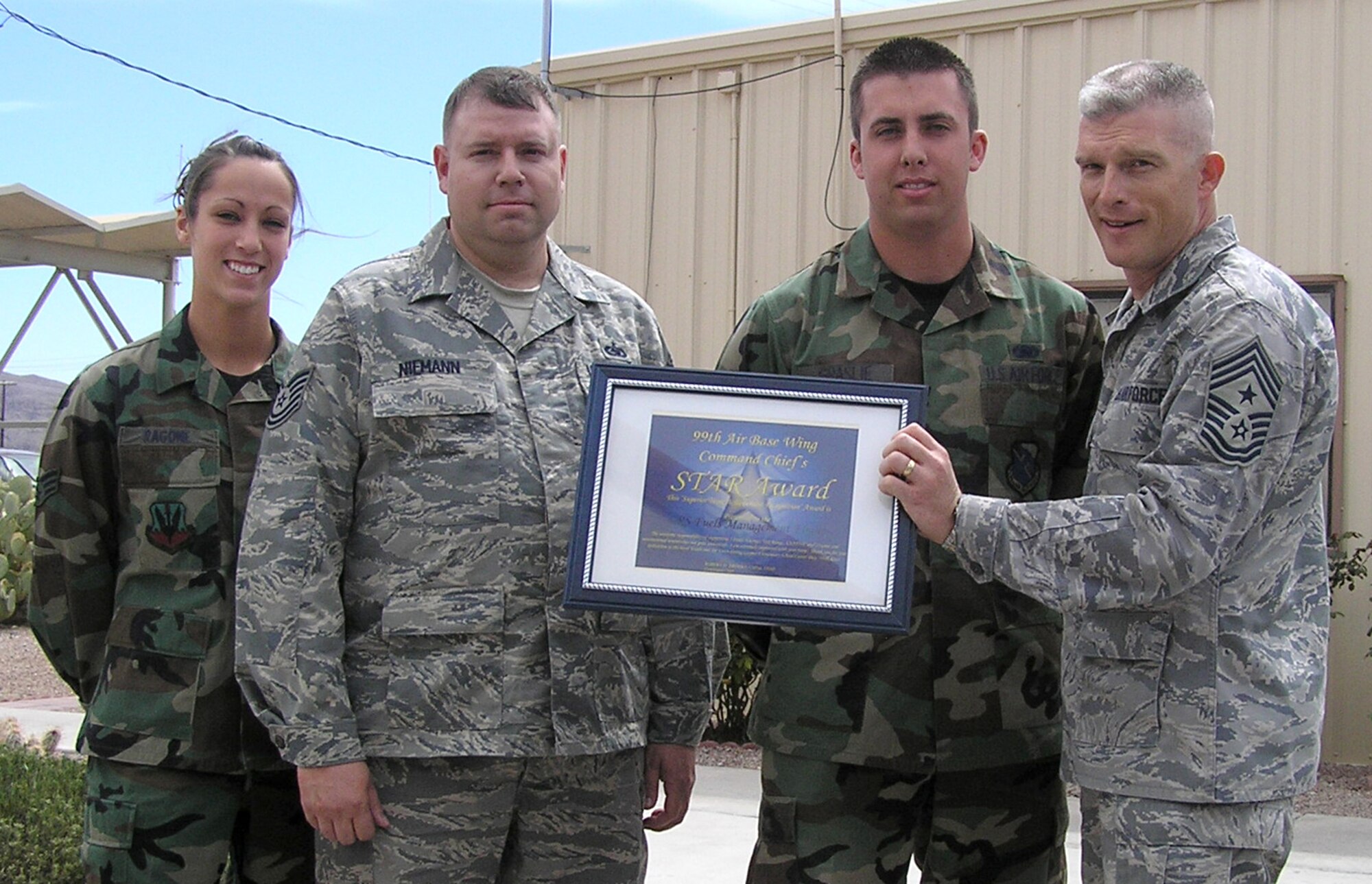 NELLIS AIR FORCE BASE, Nev.—99th Air Base Wing Command Chief Master Sgt. Robert Brooks (right) presents his monthly STAR Award, here March 28, to (left to right) Senior Airman Brittney Ragone, Tech. Sgt. Scott Niemann and Senior Airman Eric Graslie from the 99th Logistic Readiness Squadron Fuels Management Flight for their volunteer efforts at Goynes Elementary School’s career day. (U.S. Air Force photo/Senior Master Sgt. Raymond Jure)