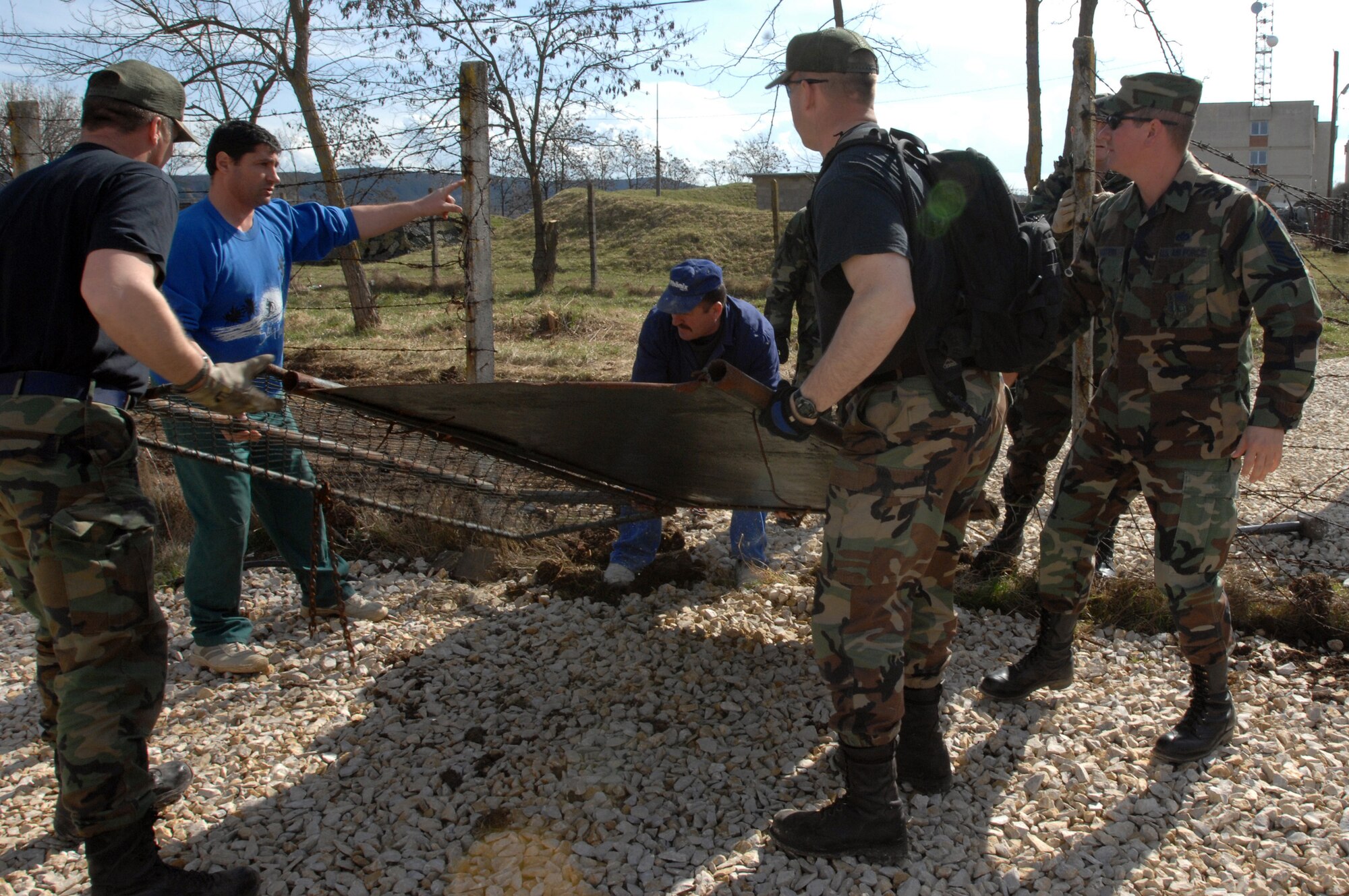 CAMPIA TURZII, Romania -- Members of the 404 Expeditionary Air Base Squadron work with Romanian nationals in removing the gate that divided the Romania base from the tent city here March 24, 2008. The deployed civil engineering team built an entire tent city here in 96 hours to support U.S. operations at the air base.  The Airmen are part of a team which is augmenting NATO forces in securing the airspace around Bucharest, Romania, for the NATO Summit April 2-4,  (U.S Air Force photo by Senior Airman Teresa M. Hawkins)
