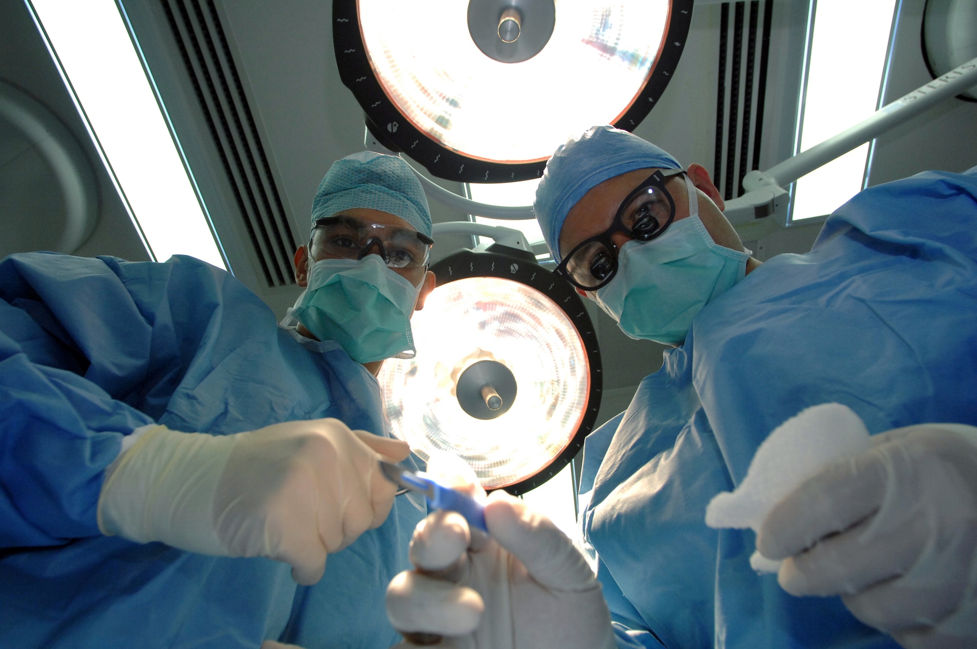 Maj. Ky Kobayashi and Airman 1st Class Emanuel White prepare for surgery on a "patient" Feb. 27 in the operating room at the Air Force Theater Hospital at Balad Air Base, Iraq. The operating room staff and doctors perform many hours of surgery daily  on servicemembers and local area citizens. Major Kobayashi is a 332nd Expeditionary Medical Operations Squadron orthopedic surgeon and Airman White is a 332nd EMDOS surgical technician. Both are deployed from Lackland Air Force Base, Texas. The photo is taken from the patient's perspective. (U.S. Air Force photo/Senior Airman Julianne Showalter) 