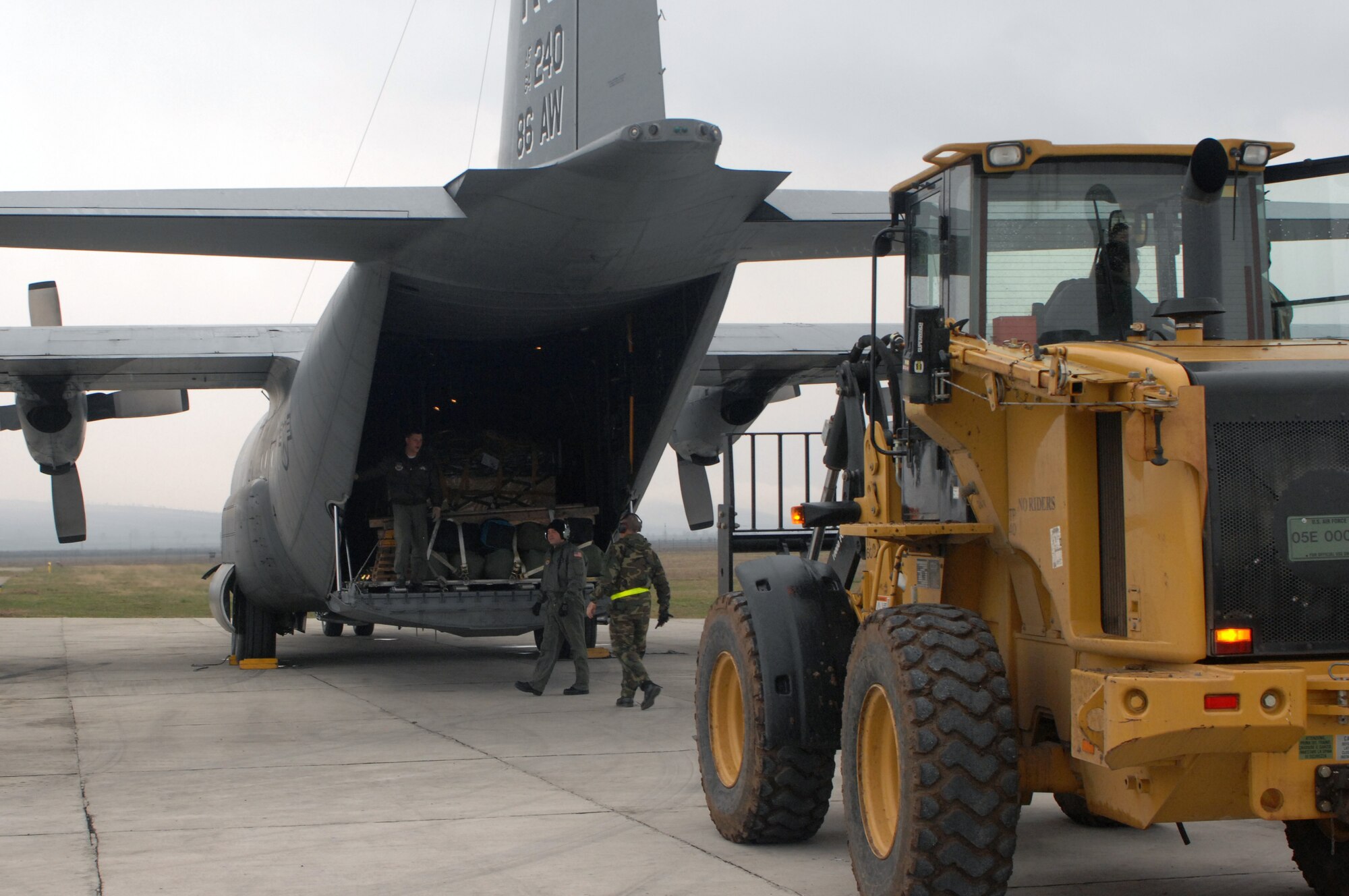 CAMPIA TURZII, Romania -- Members of the 404th Expeditionary Air Base Squadron prepare to unload pallets from a 86th Airlift Wing C-130 dropping off cargo and personnel here Mar. 25, 2008. A four-man team of Airmen received and processed more than 500,000 pounds of cargo here toward building up U.S. operations at the base in support of the NATO Summit.  The U.S forces are augmenting NATO by providing infrastructure and aircraft for the duration of summit in Bucharest Apr. 2-4.  (U.S. Air Force photo by Senior Airman Teresa M. Hawkins)(Released)
