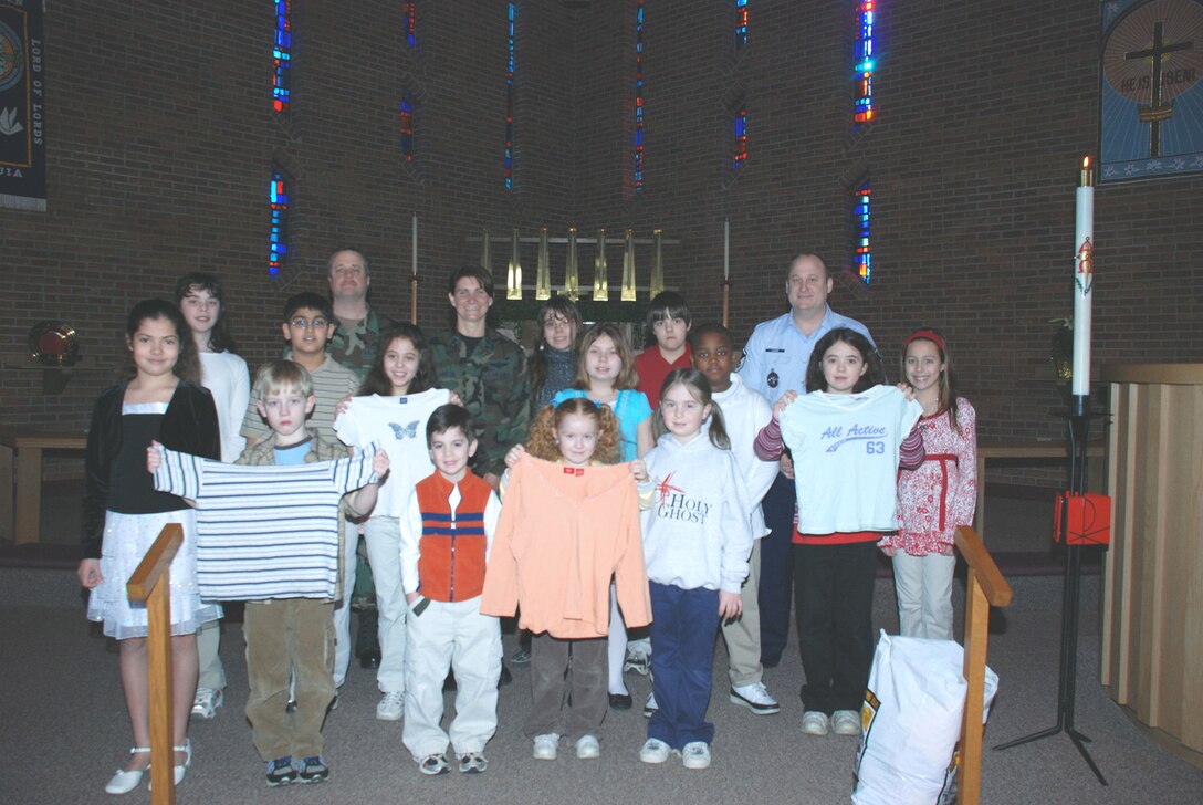 A group of Holy Ghost students present 107th ARW members with some of the clothes they collected for children in Iraq who are in need on March 26.  The clothes will be sent to Iraq where deployed members of the 107th security forces will distribute them to the children. Front row from left: Alyssa, Ben, Luke Wish, Amanda, Ellen.  Second row from left:  Alicia, Vishel, Lexi, Stephanie, Keonte, Jessica.Back row from left: Tech. Sgt. Chris Zastrow, Lt. Col. Deanna Miller, Sharleen, Stephen, Master Sgt. Bryan Lange.(US Air Force photo by Staff Sgt. Rebecca Kenyon)