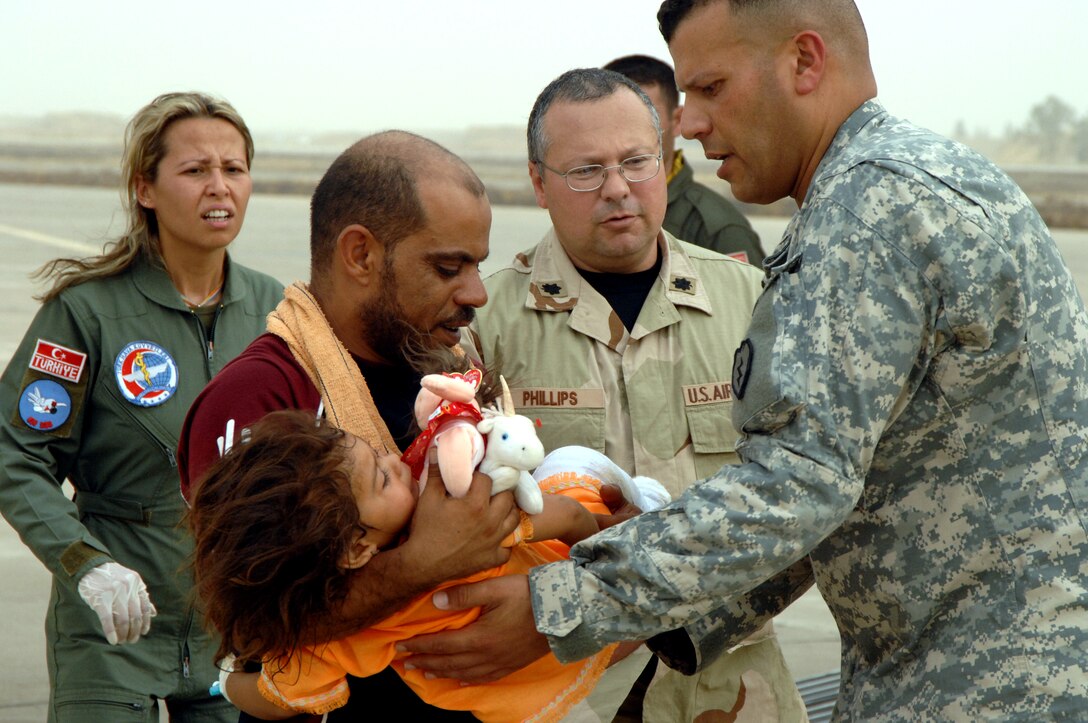 A U.S. Air Force airman from 506th Air Expeditionary Group, a U.S. Army Soldier and a Turkish air force member transport an Iraqi child to safety during a multinational humanitarian airlift effort on Kirkuk Regional Air Base, Iraq, July 8, 2007. The victim was hurt in an attack in Tuz Khurmato, Iraq. Airmen from the 506th Air Expeditionary Group and Turkish army and air force members worked together to receive, transfer and medevac almost 30 injured Turkmen civilians and family members to the Turkish capital city of Ankara for further treatment. U.S. Air Force photo by Senior Airman Kristin Ruleau