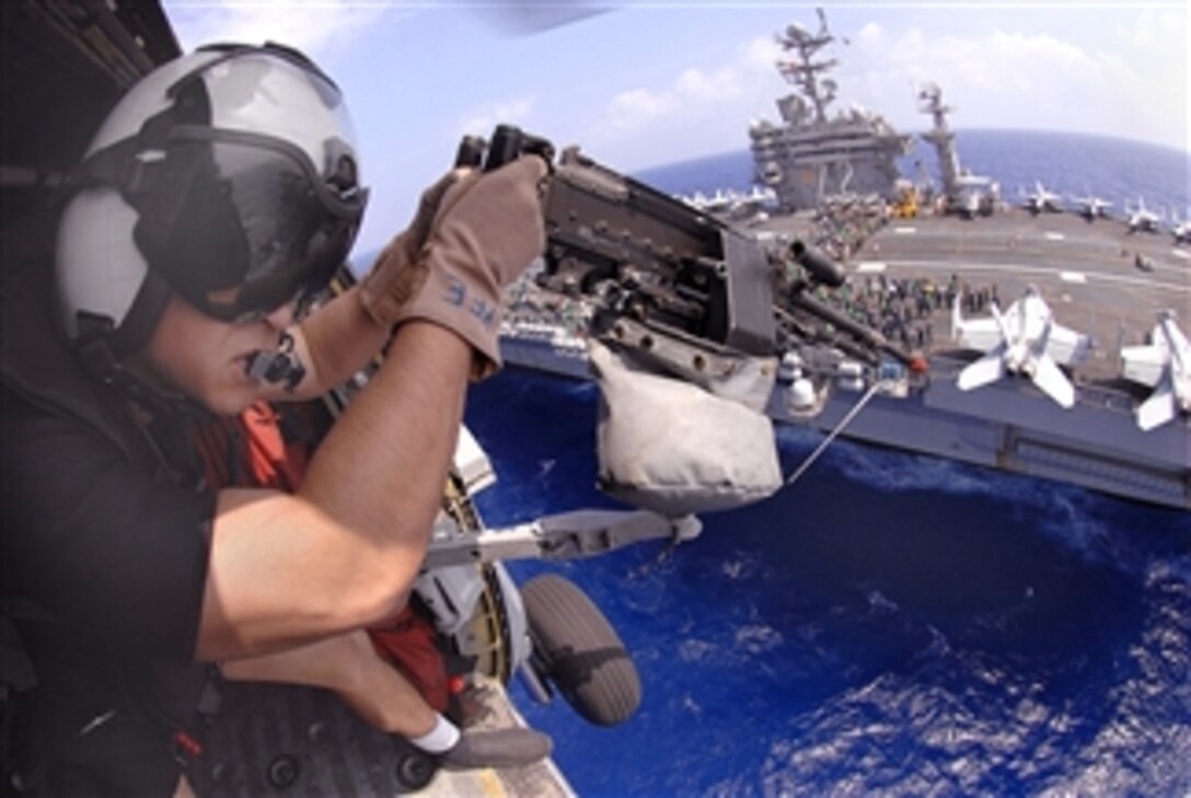 U.S. Navy Petty Officer 2nd Class Tyler Yee mans an M-240 machine gun while flying in a Seahawk helicopter over the Nimitz-class aircraft carrier USS Abraham Lincoln, March 30, 2008, during an air power demonstration over the Pacific Ocean. 