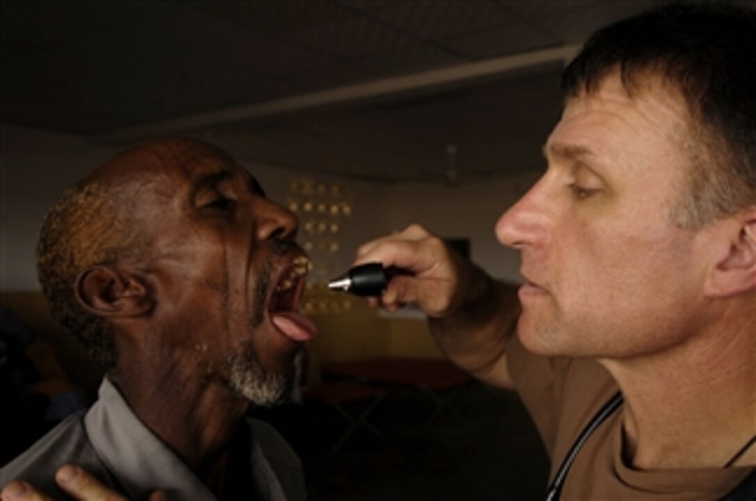 U.S. Navy Cmdr. Alan Philippi examines the throat of a man during a medical civil action project in Goubetto Village in Djibouti on March 29, 2008.  Philippi is a Navy doctor working with service members assigned to 354th Civil Affairs Brigade, Special Functioning Team, Combined Joint Task Force - Horn of Africa, during a six-day medical project.  