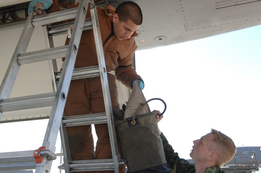Airman 1st Class Kyle Stinger hands Airman 1st Class Dustin Lozano, 28th Aircraft Maintaince Squadron Aerospace Propulsion technicians, a soak rag April 2 during the base Operational Readiness Inspection. Soak rags are used to clean hydraulic coolant liquid out of the B-1 Lancer forward weapons bay. The 28th Bomb Wing was evaulated on it's ability to deploy rapidly when the need arises.  (U.S. Air Force photo/Airman Corey Hook)