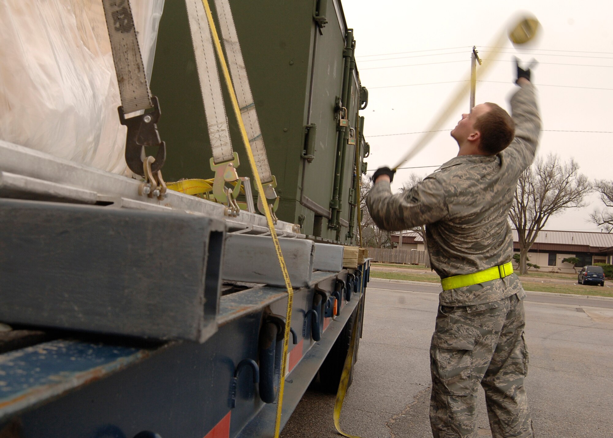 MCCONNELL AIR FORCE BASE, Kan. -- Airman 1st Class Ryan Hogue, 22nd Logistics Readiness Squadron, throws a cargo strap over a pallet, March 30, to prepare for a simulated deployment during an Operational Readiness Exercise. The crates and pallets, carrying brakes and tires, went to a cargo deployment function yard to simulate mobility. (Photo by Airman 1st Class Maria Ruiz)