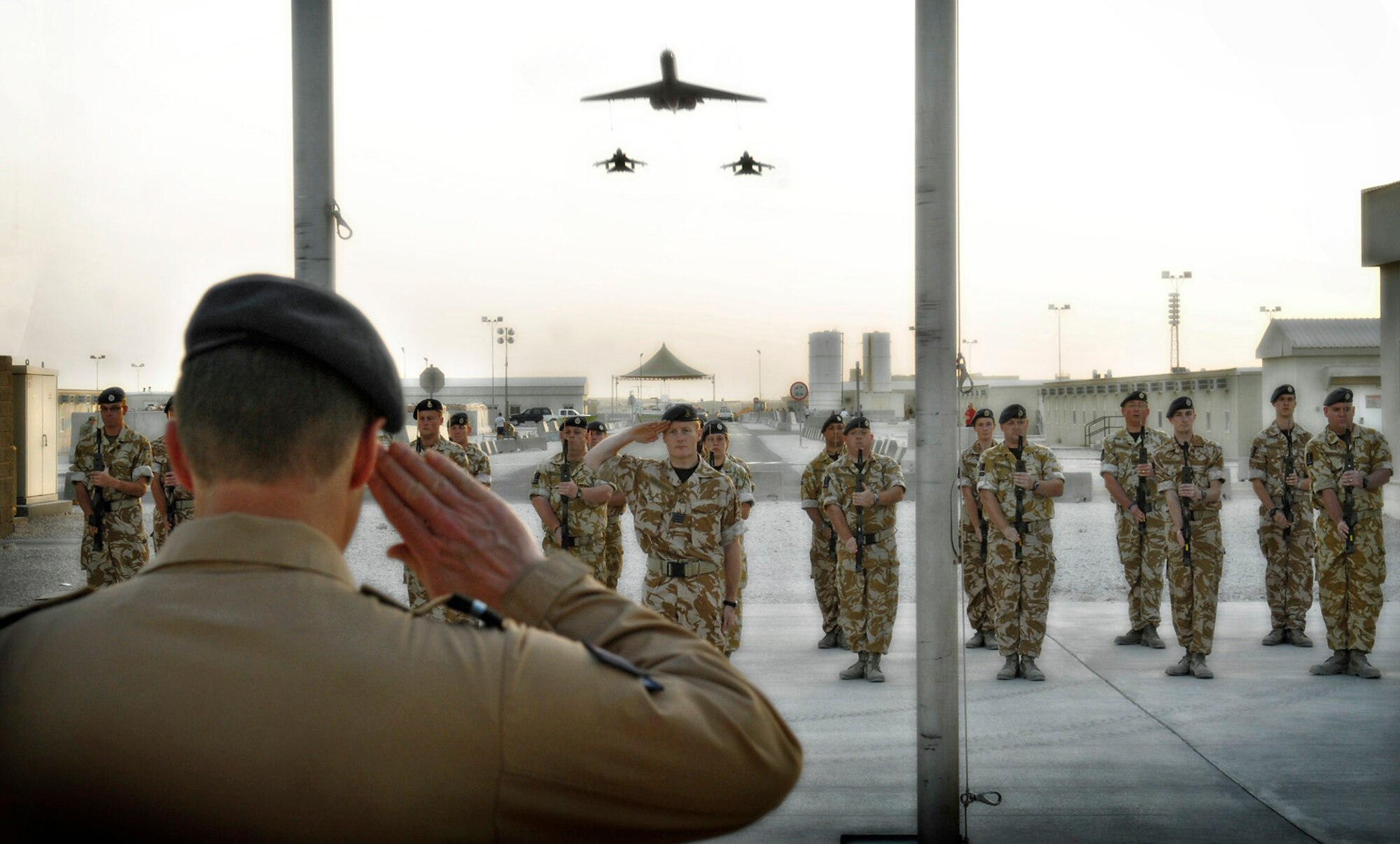 Squadron Leader Mark Wright renders a salute at a sunset ceremony in celebration of the 90th Anniversary of the Royal Air Force, April 1, as two RAF GR-4 Tornados from the 14th Squadron and a VC10 tanker from the Number 101 Squadron perform a fly over. The ceremony concluded with the raising of the Royal Air Force Ensign toward the sky. (RAF photo/Sergeant Gary Morgan)