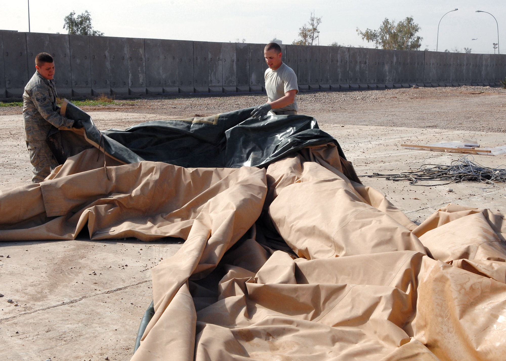 Senior Airmen Lewis Paine and Ivan Alandzak prepare a portion of a tent Feb. 29 for shipment to the National Museum of Health and Medicine in Washington where it is slated for exhibition. The tent was part of the origianal Air Force Theater Hospital at Balad Air Base, Iraq. The medical community considers the tent to be the place where the most American blood was spilled since the Vietnam War. Airman Paine is a 332nd Expeditionary Civil Engineer Squadron power production journeyman deployed from Ellsworth, S.D. and Airman Alandzak is a 332nd ECES liquid fuel journeyman deployed from Malmstrom Air Force Base, Mont. (U.S. Air Force photo/Senior Airman Julianne Showalter) 