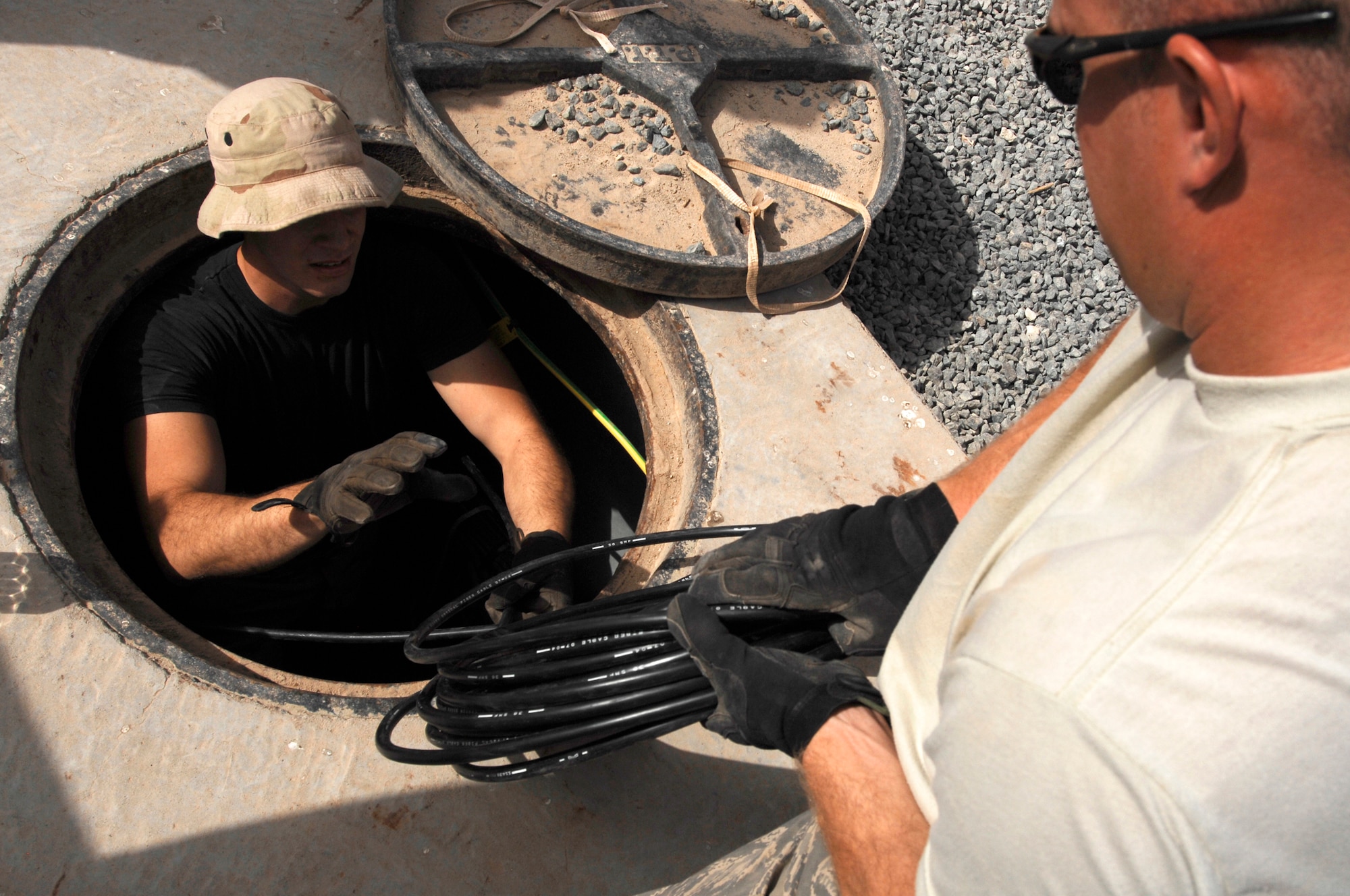 SOUTHWEST ASIA -- Staff Sgt. Christopher Billings, (right), hands Airman 1st Class Theodore Nichols a bundle of fiber-optic cable March 31, 2008, at an air base in the Persian Gulf Region. The installation of the new cable will provide world wide communication access to living quarters on the base. Sergeant Billings and Airman Nichols are both cable communication and antenna maintenance specialists deployed to the 386th Expeditionary Communications Squadron. Sergeant Billings is deployed from the 85th Engineering and Installation Squadron, Keesler Air Force Base, Miss. and Airman Nichols is deployed from the 96th Communication Squadron, Eglin AFB, Fla. (U.S. Air Force photo/ Staff Sgt. Patrick Dixon)