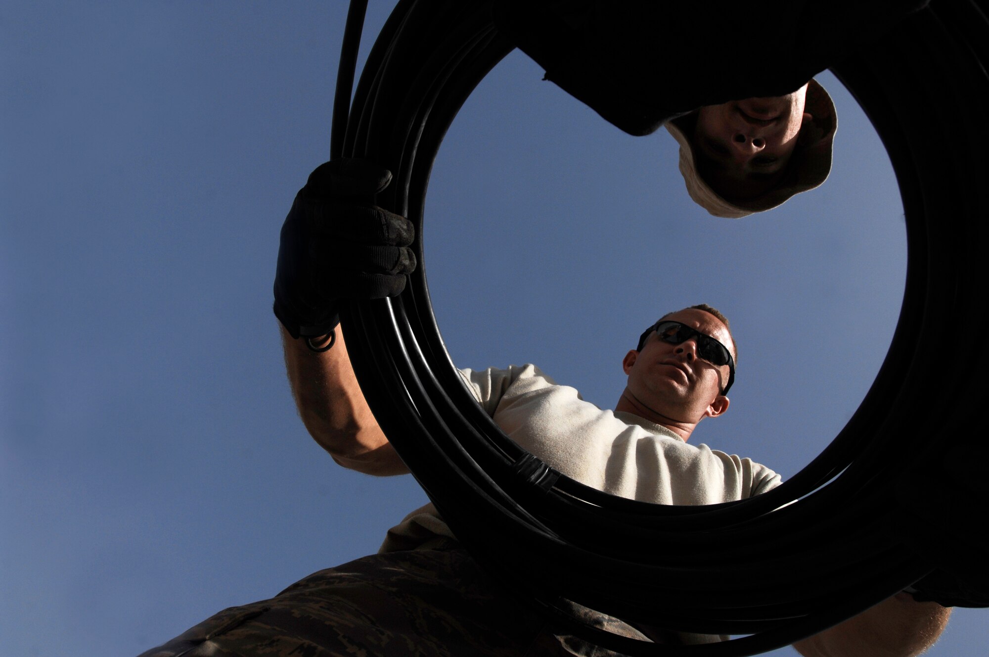 SOUTHWEST ASIA -- Staff Sgt. Christopher Billings, (bottom), and Airman 1st Class Theodore Nichols wrap up a bundle of fiber-optic cable March 31, 2008, at an air base in the Persian Gulf Region following the installation of a new cable to provide world wide communication access to living quarters on the base. Sergeant Billings and Airman Nichols are both cable communication and antenna maintenance specialists deployed to the 386th Expeditionary Communications Squadron. Sergeant Billings is deployed from the 85th Engineering and Installation Squadron, Keesler Air Force Base, Miss. and Airman Nichols is deployed from the 96th Communication Squadron, Eglin AFB, Fla. (U.S. Air Force photo/ Staff Sgt. Patrick Dixon)