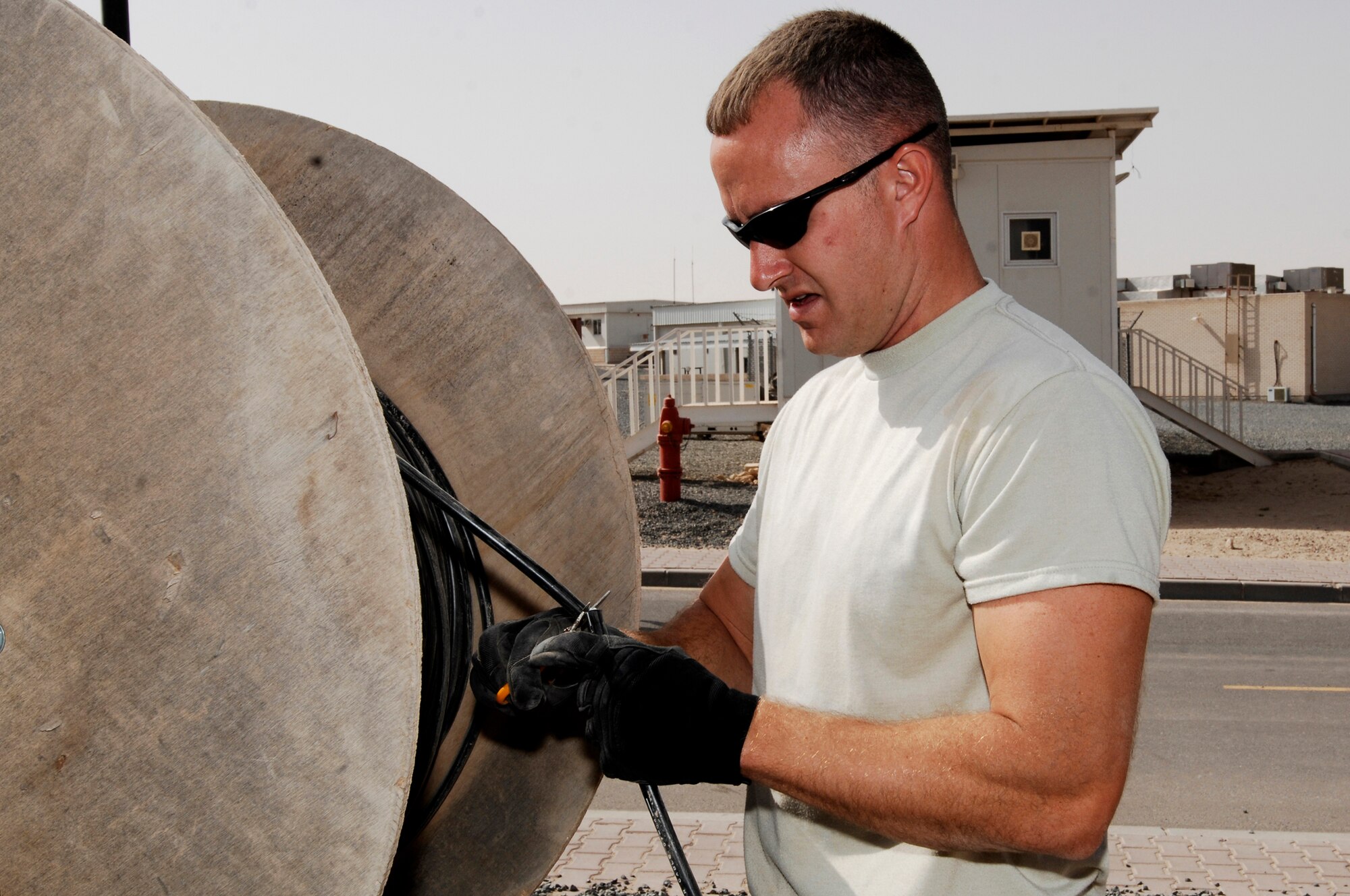 SOUTHWEST ASIA -- Staff Sgt. Christopher Billings, a cable communication and antenna maintenance specialist deployed to the 386th Expeditionary Communications Squadron, cuts a piece of fiber-optic cable March 31, 2008, at an air base in the Persian Gulf Region. The new cable will provide world wide communication access to living quarters on the base. Sergeant Billings is deployed from the 85th Engineering and Installation Squadron, Keesler Air Force Base, Miss. (U.S. Air Force photo/ Staff Sgt. Patrick Dixon)