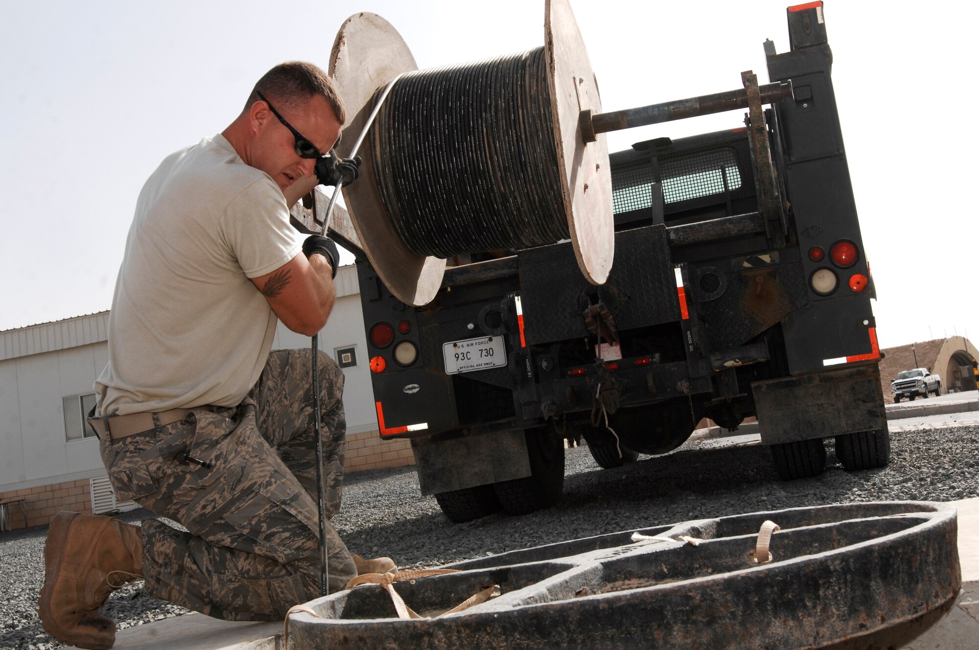 SOUTHWEST ASIA -- Staff Sgt. Christopher Billings, a cable communication and antenna maintenance specialist with the 386th Expeditionary Communications Squadron, feeds fiber-optic cable into a manhole March 31, 2008, at an air base in the Persian Gulf Region. The new cable will provide world wide communication access to living quarters on the base. Sergeant Billings is deployed from the 85th Engineering and Installation Squadron, Keesler Air Force Base, Miss. (U.S. Air Force photo/ Staff Sgt. Patrick Dixon)